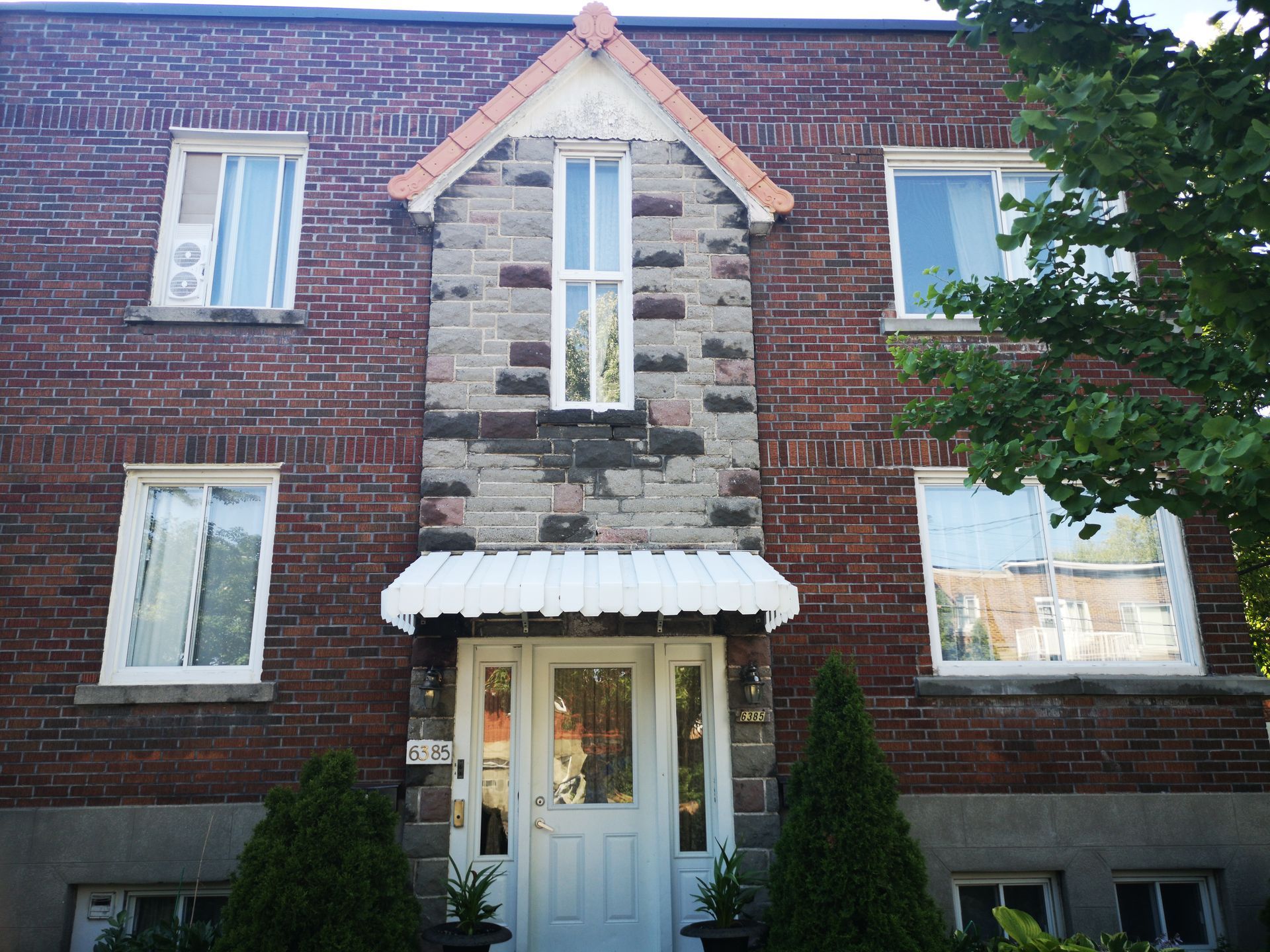 Un bâtiment en brique avec une porte blanche et un auvent blanc