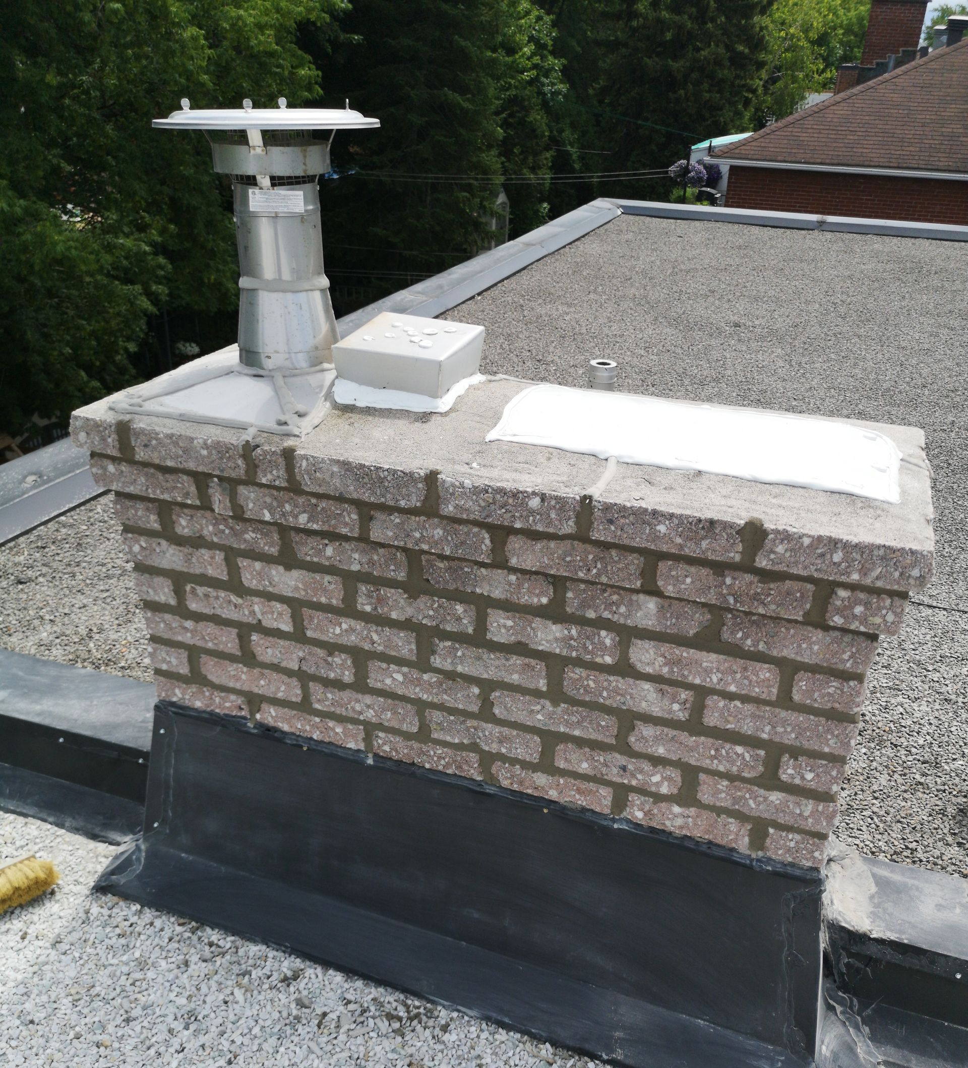 Une cheminée en brique se trouve au sommet d’un toit.