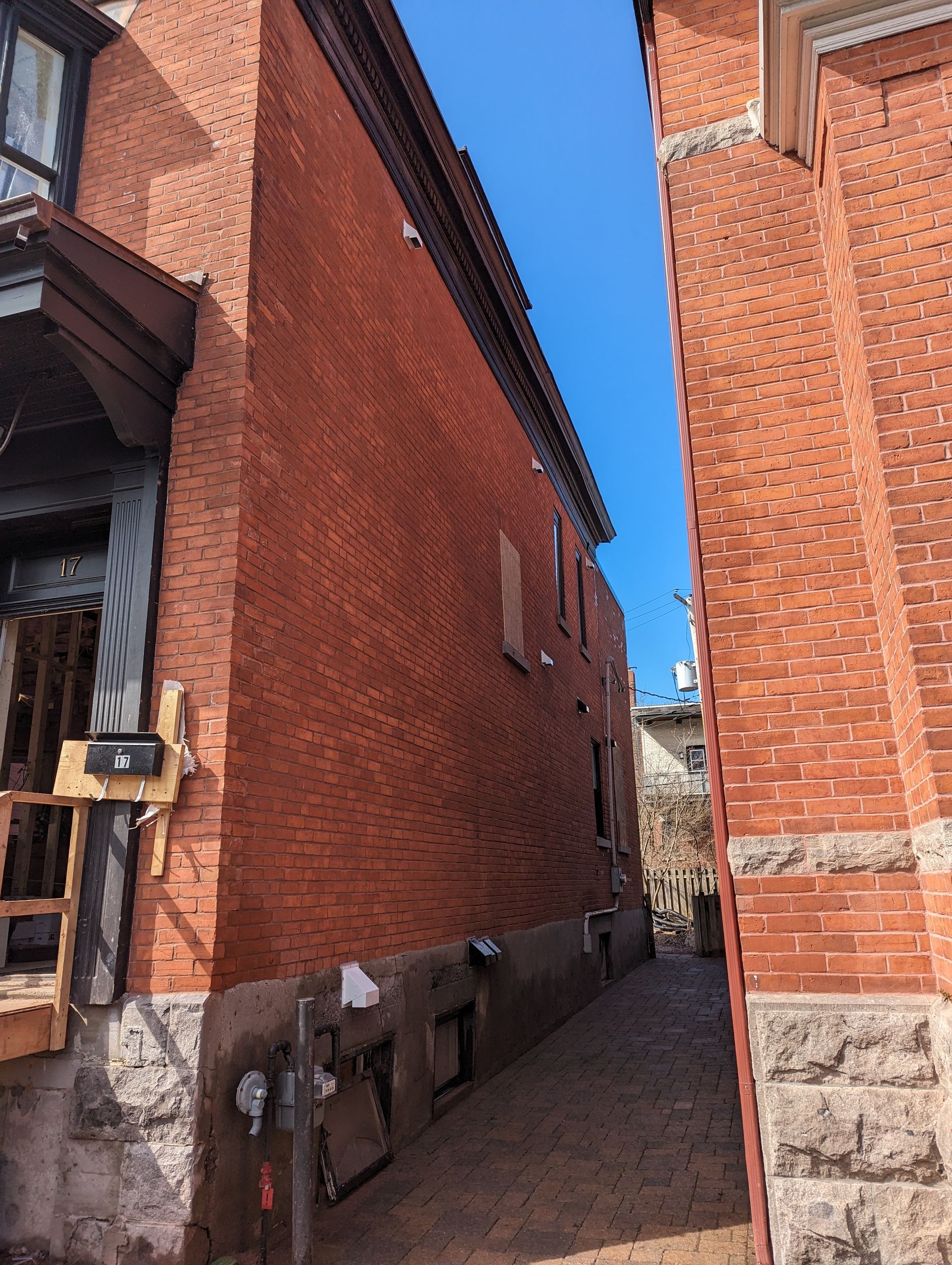Une ruelle étroite entre deux bâtiments en brique par une journée ensoleillée.