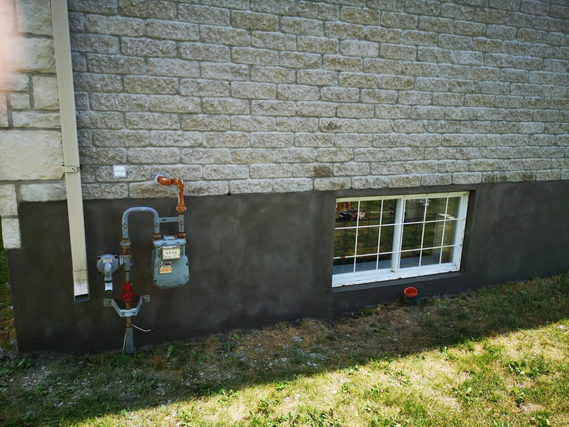 Un mur de briques avec une fenêtre et un compteur de gaz