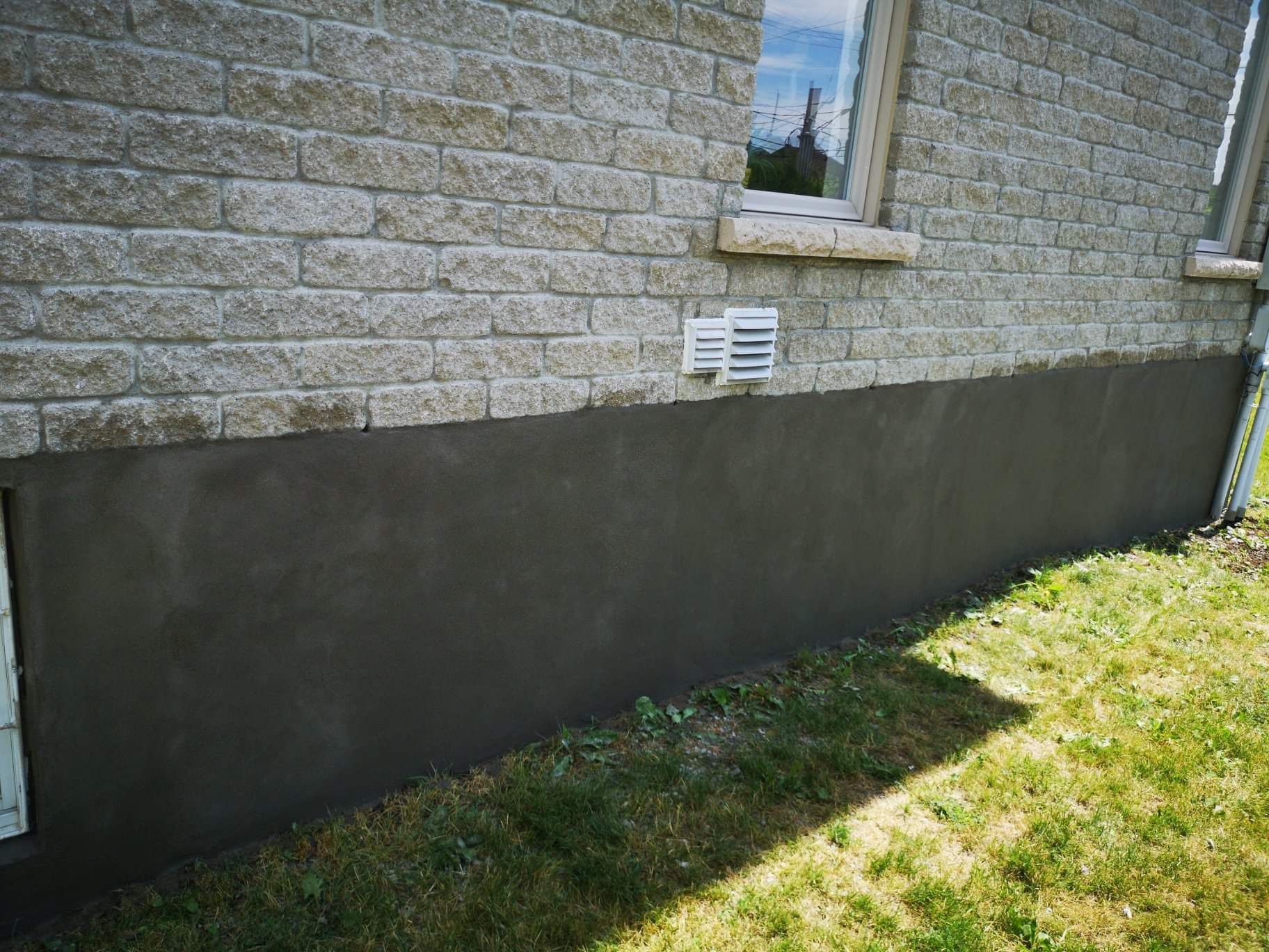 Une maison en brique avec une fenêtre et un drain sur le côté.
