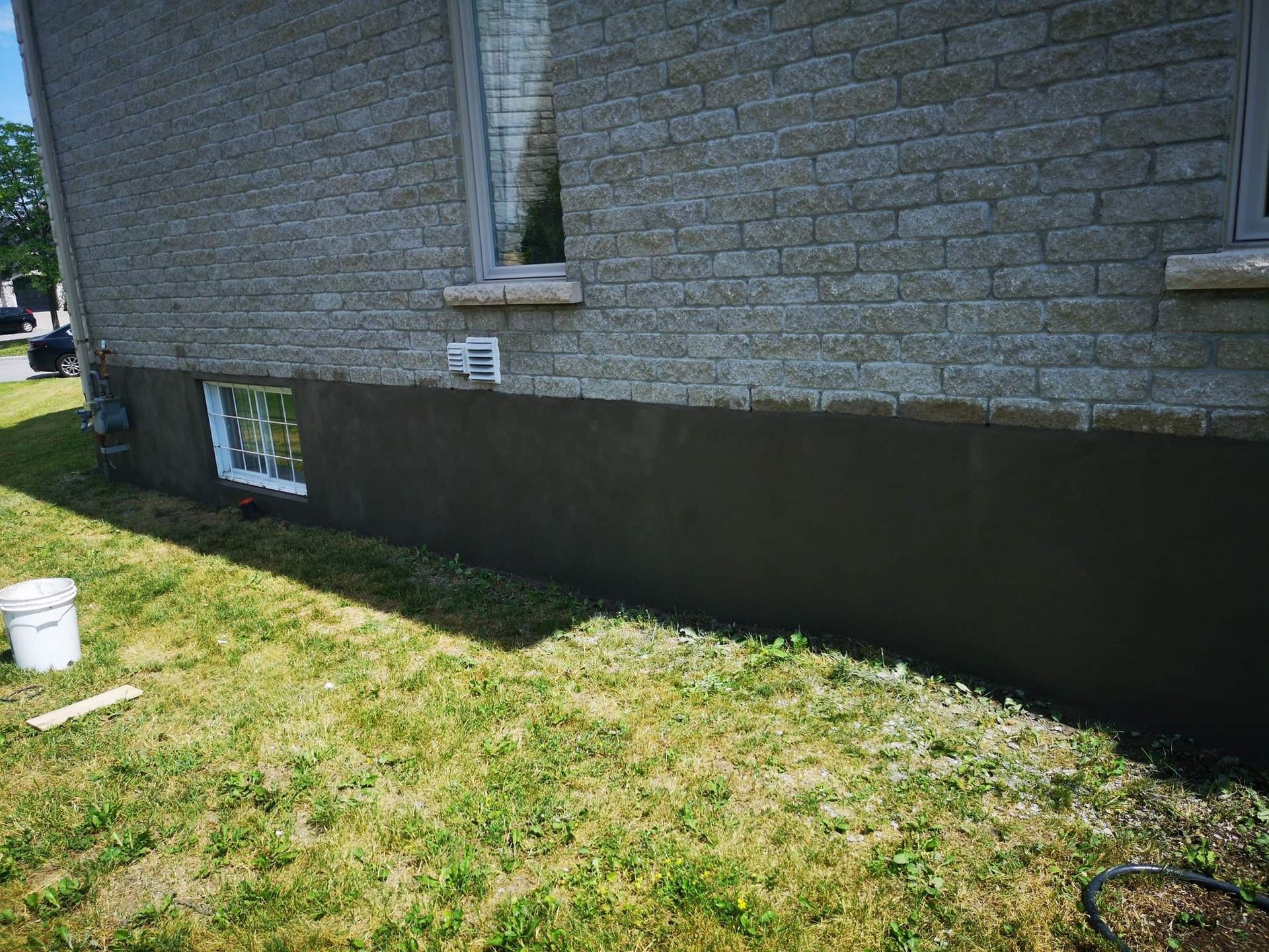 Le côté d’une maison en brique est en train d’être peint.