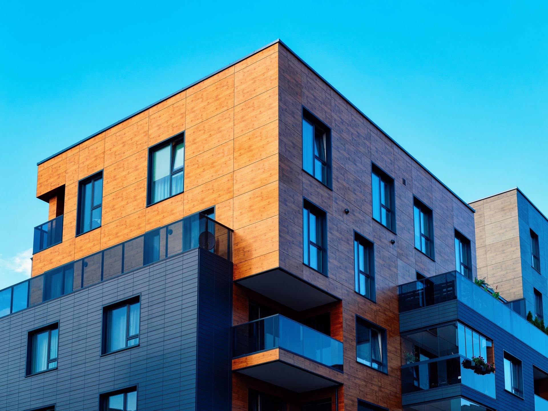 Immeuble d'appartements moderne avec des façades orange, grises et bleues sur fond de ciel bleu vif.