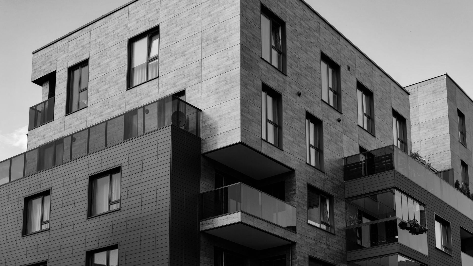 Immeuble d'appartements moderne à plusieurs étages avec balcons, noir et blanc.