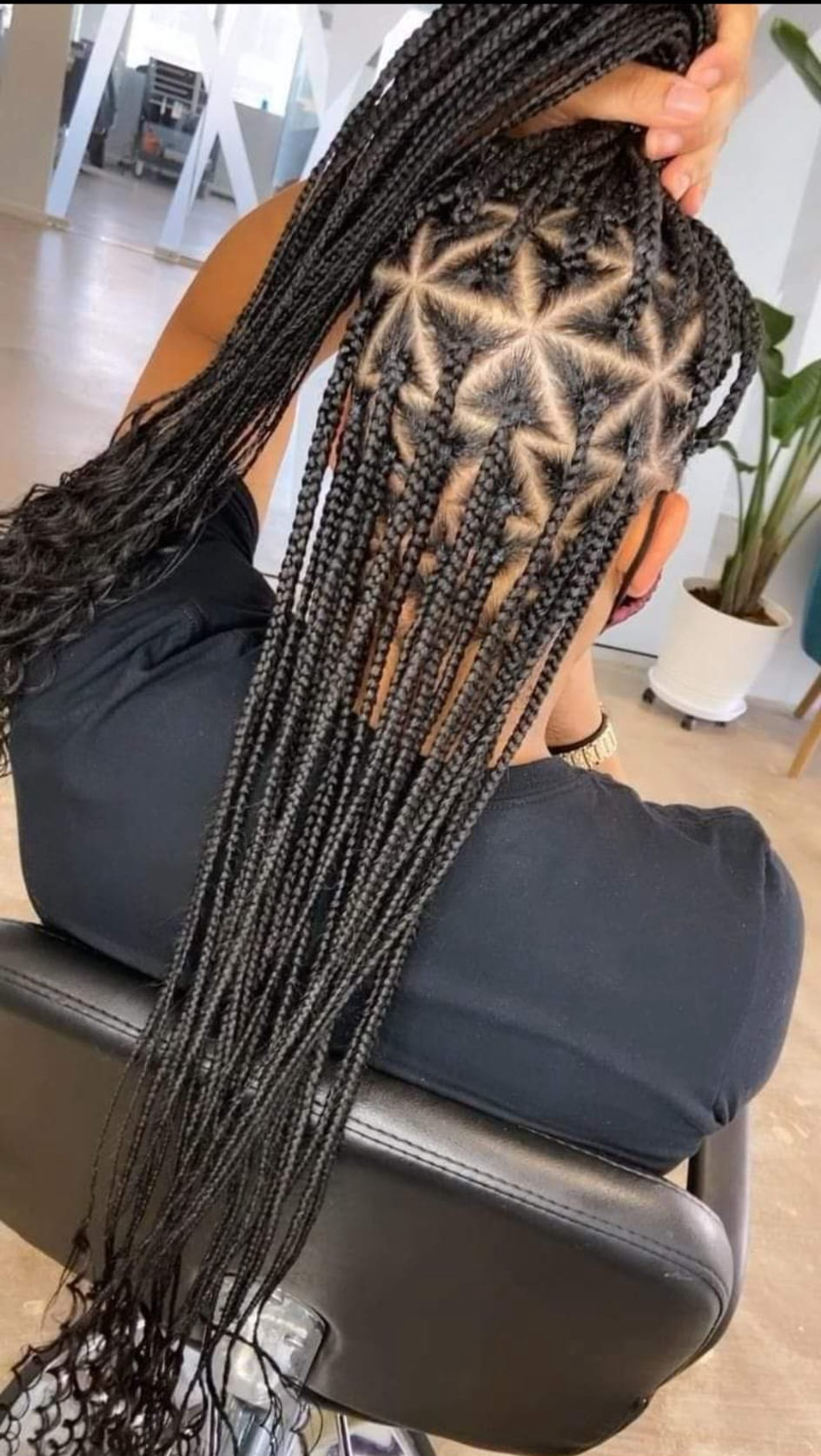 A woman with braids in her hair is wearing a grey sweater.