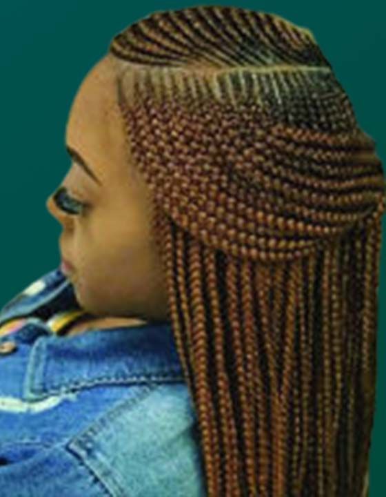 A woman with braids in her hair is wearing a denim jacket.