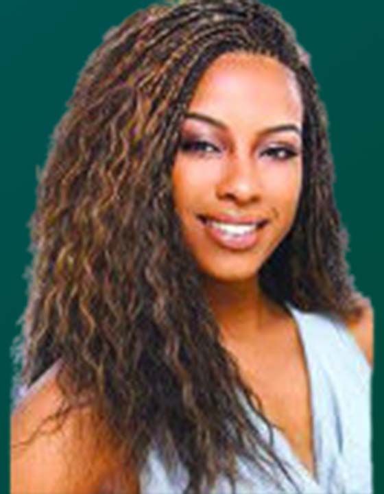 A woman with braided hair is smiling for the camera