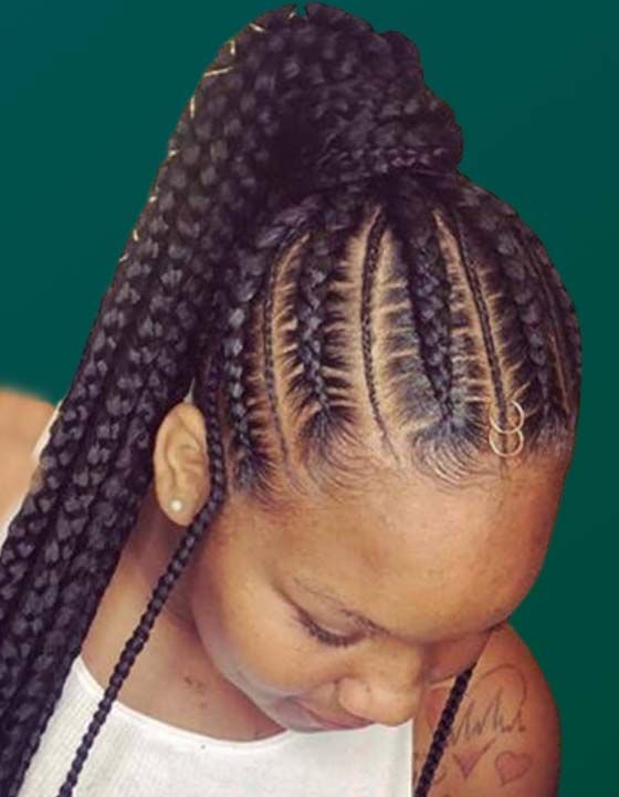 A woman with braids in her hair is wearing a white tank top.