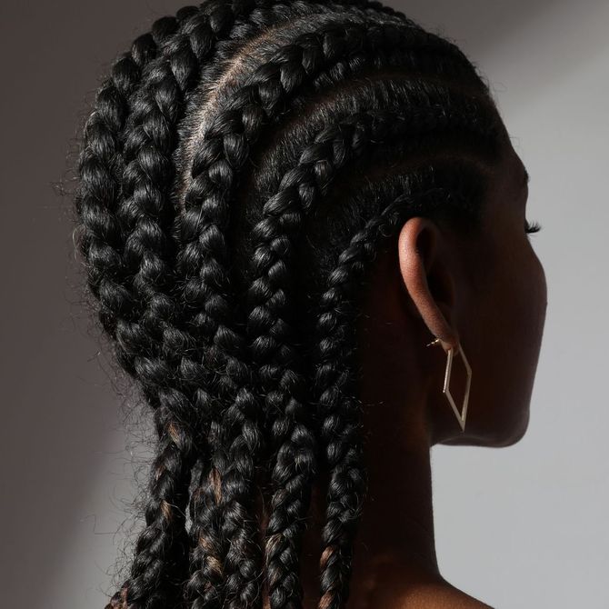 The back of a woman 's head with braids and earrings.