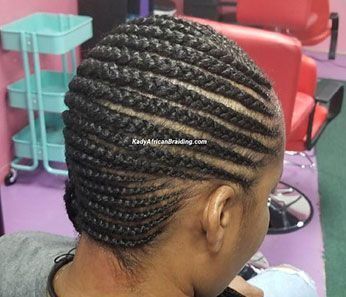 A woman is getting her hair braided in a salon.