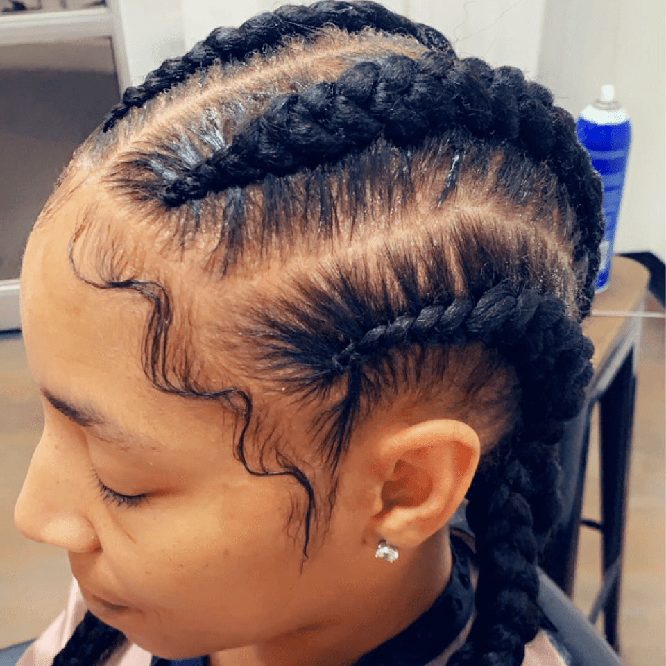 A woman with braids in her hair is sitting in a chair.