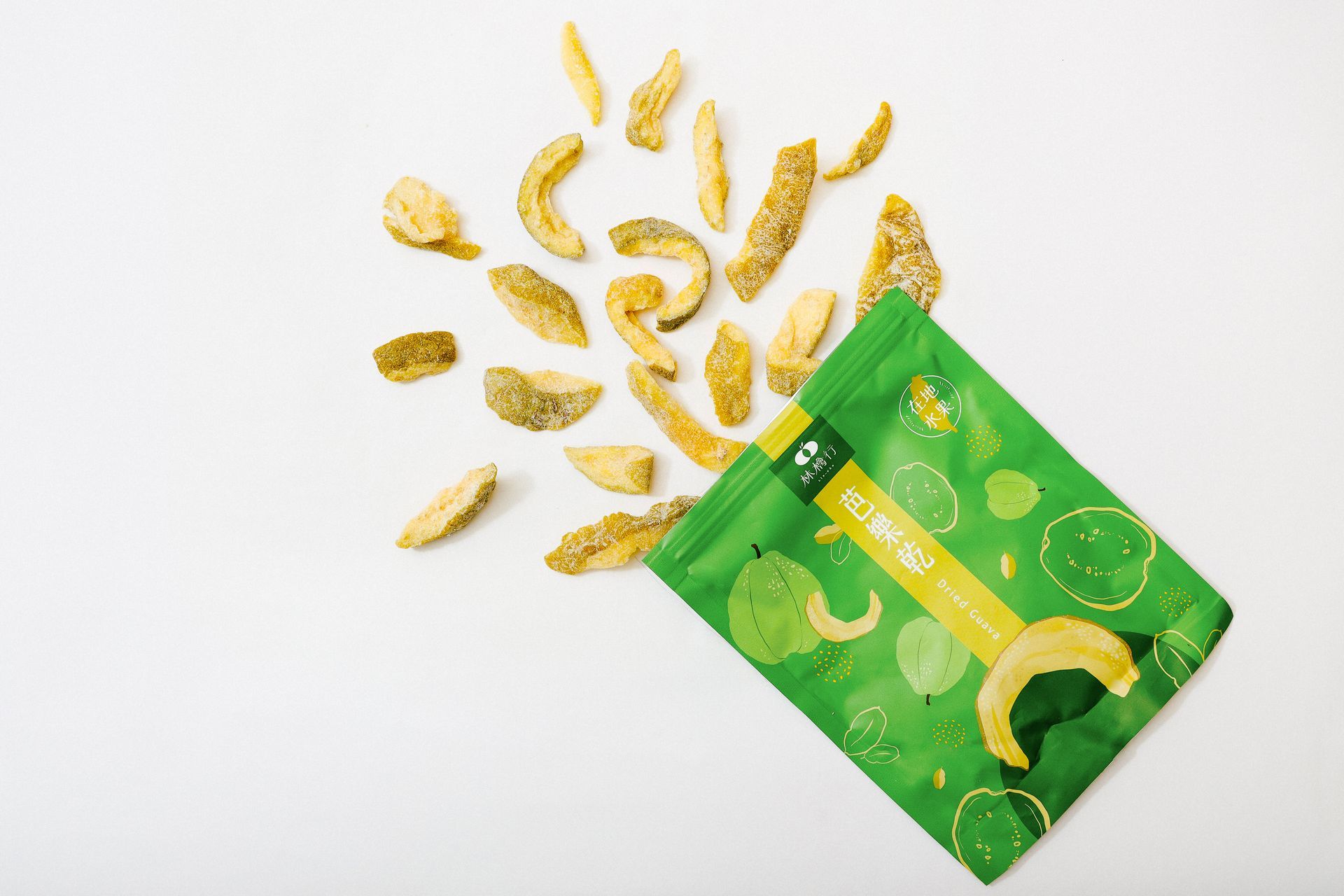 Dried guava slices spilling out of a green package onto a white surface.