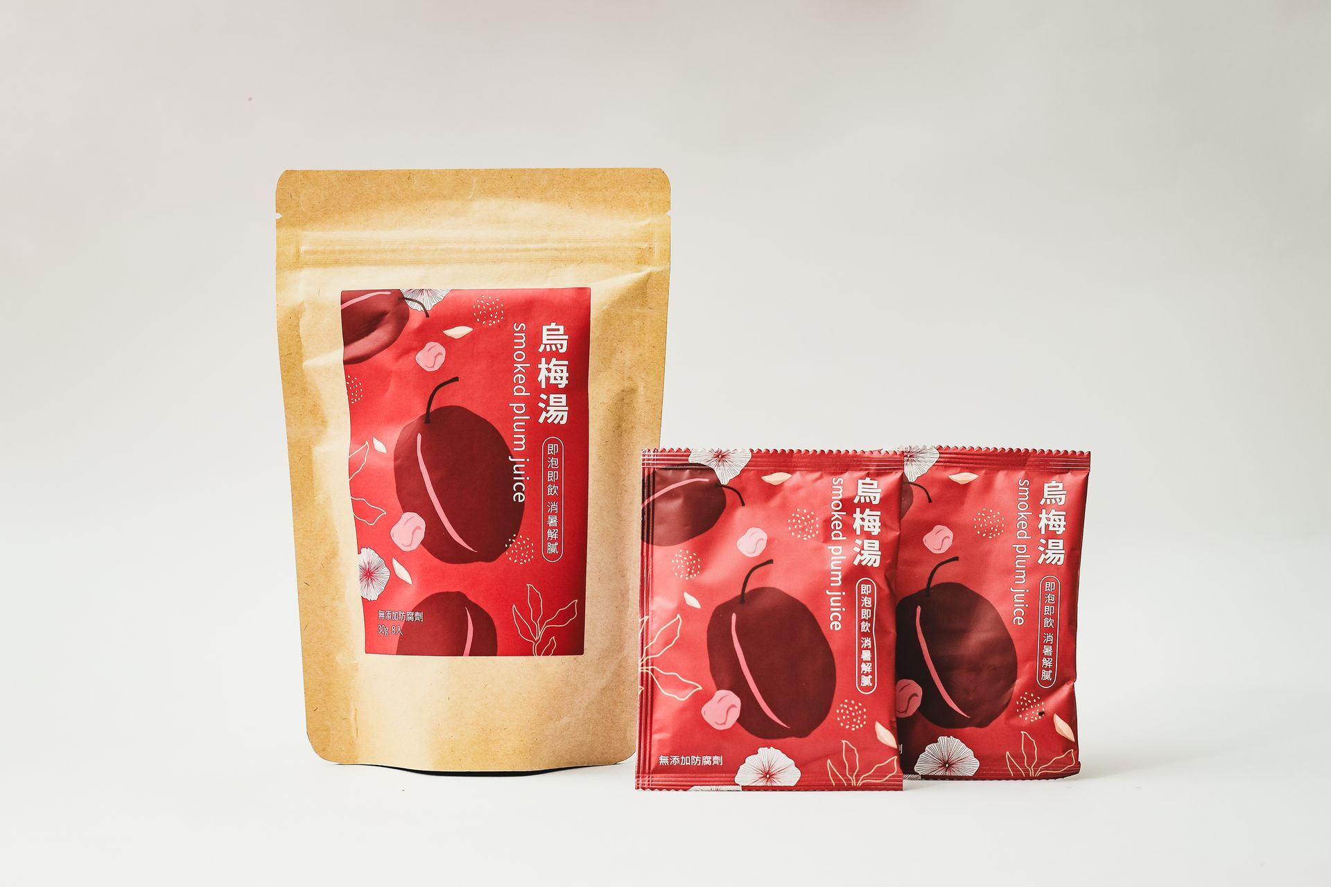 A large stand-up pouch and two smaller snack packets featuring red plum illustrations against a pale background.