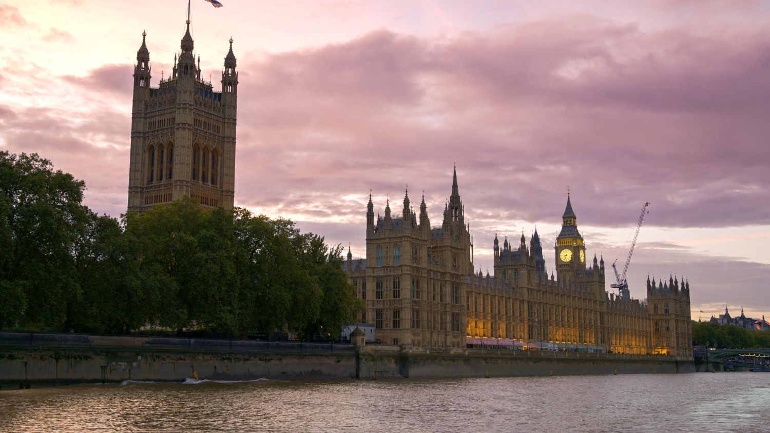 Houses of Parliament, London, at sunset; orange sky, building reflections on water.