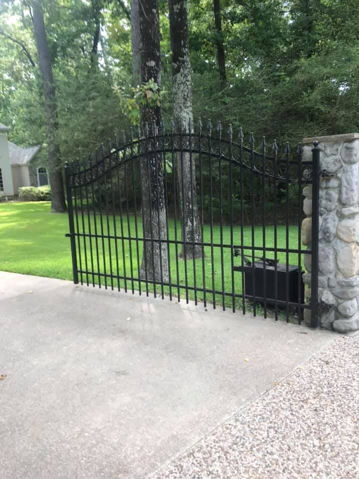 A wrought iron gate leading to a lush green yard