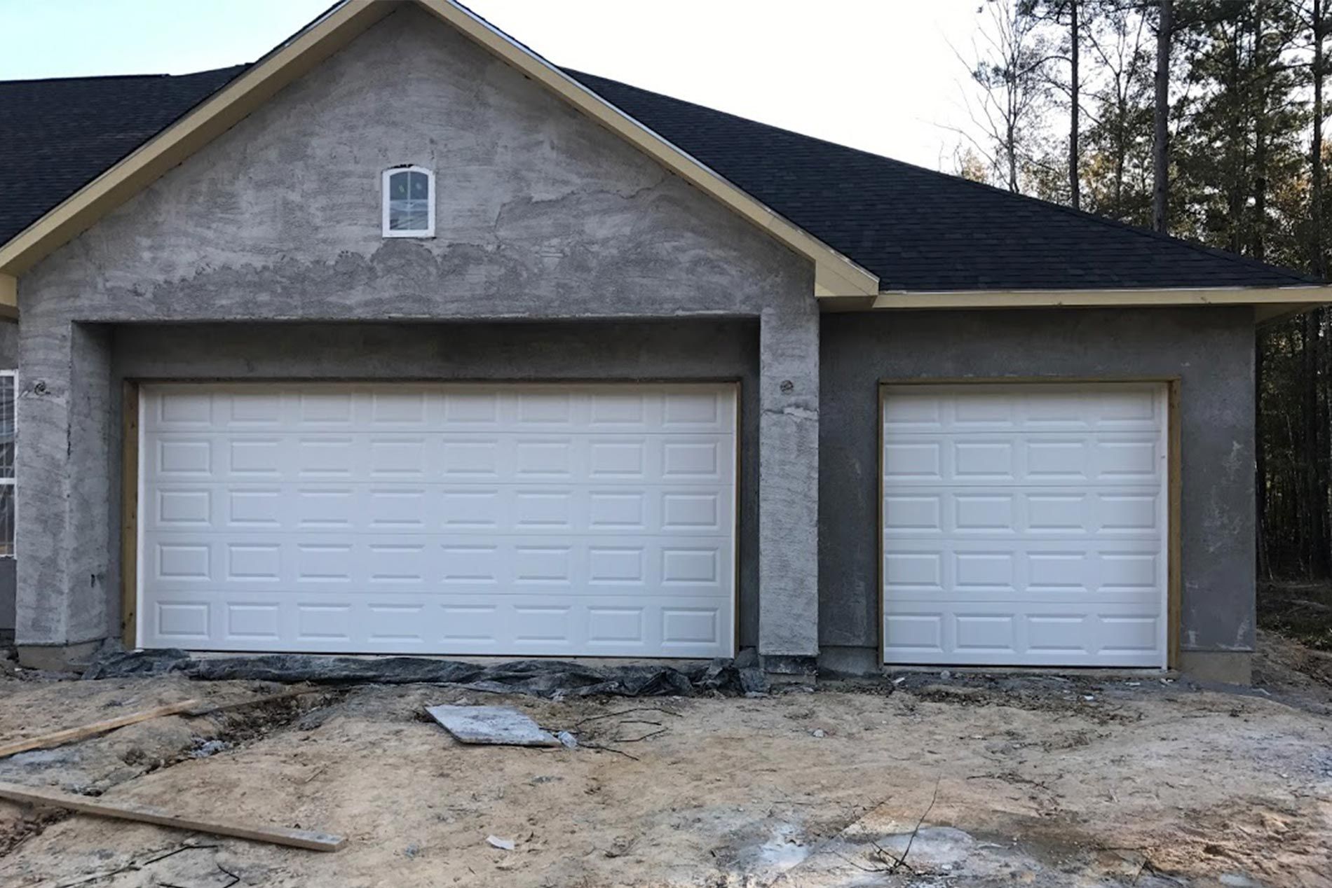A house with two white garage doors and a black roof