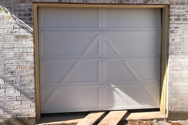 A white garage door is open on a brick wall