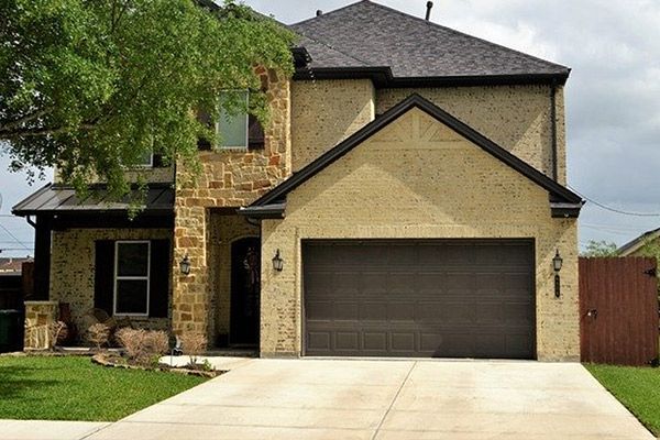 A large brick house with a brown garage door