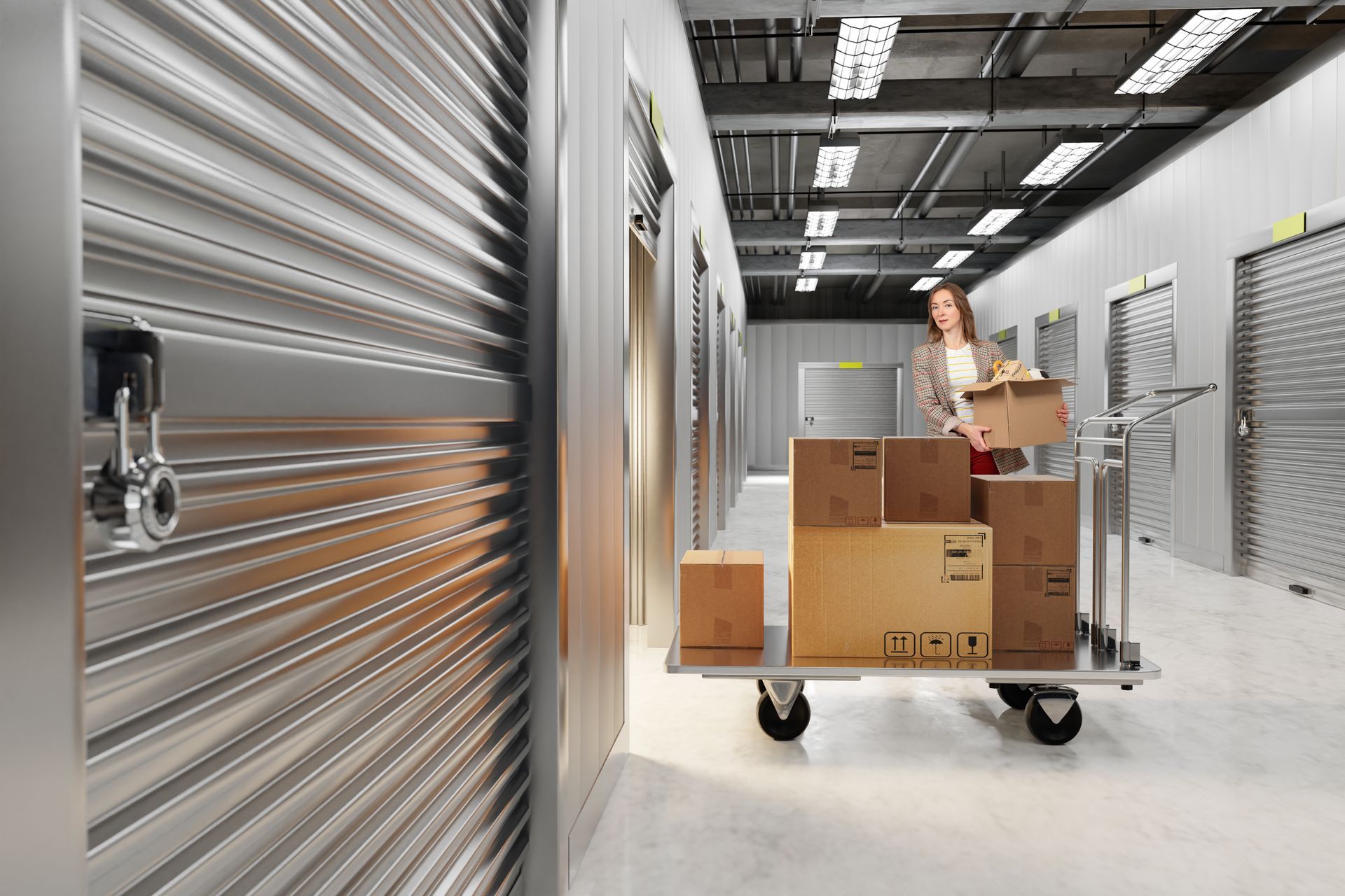 Customer with cart showcasing self-storage facility corridor while moving packed boxes.