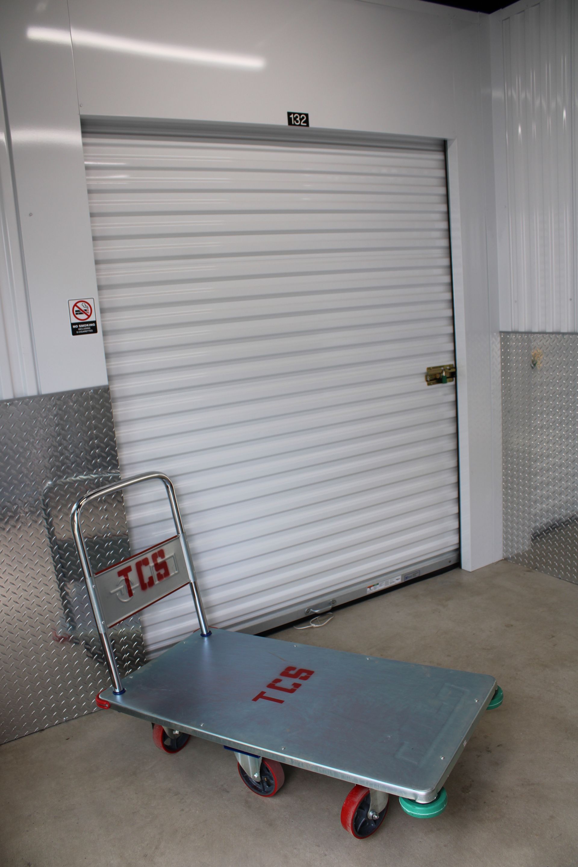 A metal cart is sitting in front of a garage door.