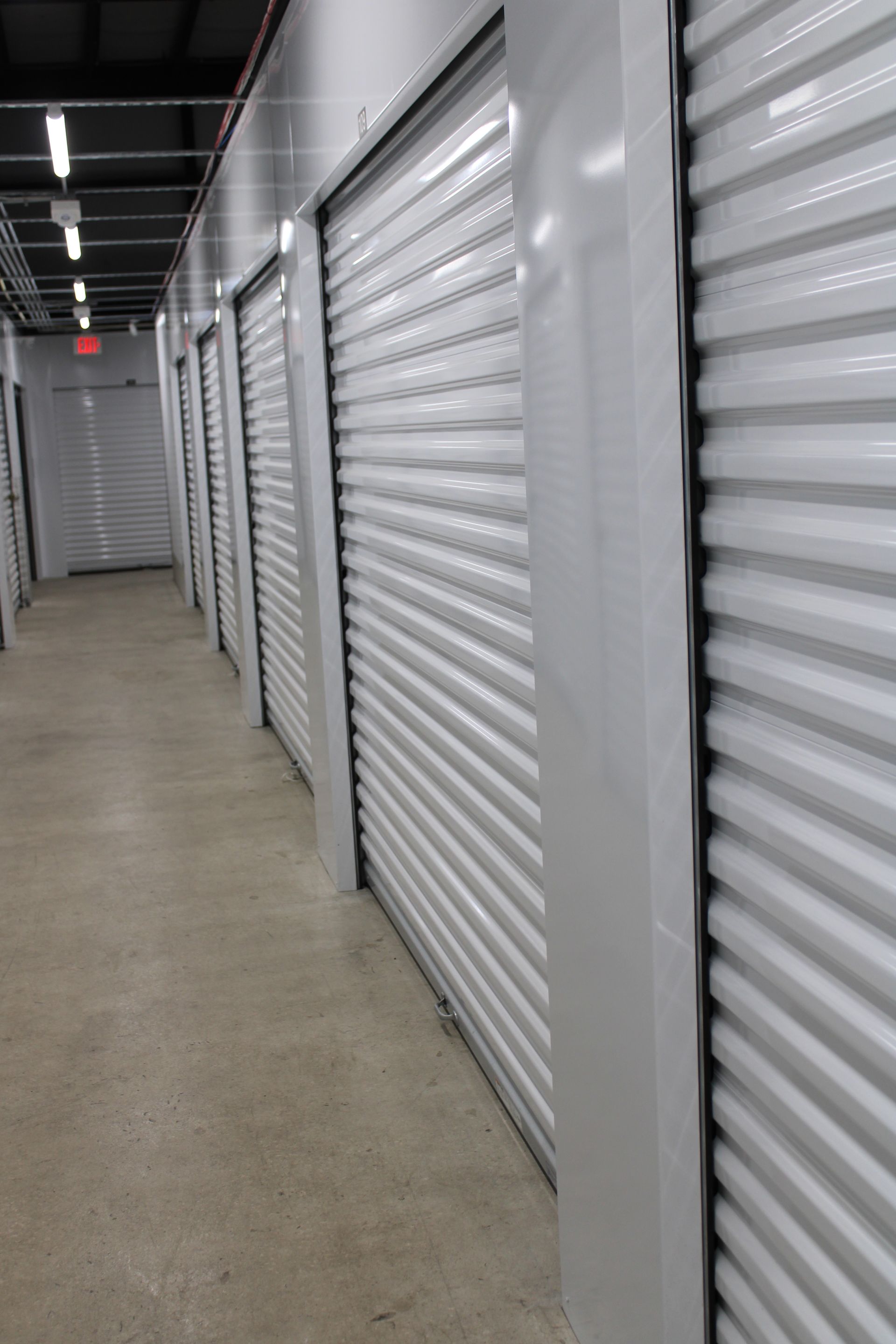A row of empty storage units with white shutters on the doors.