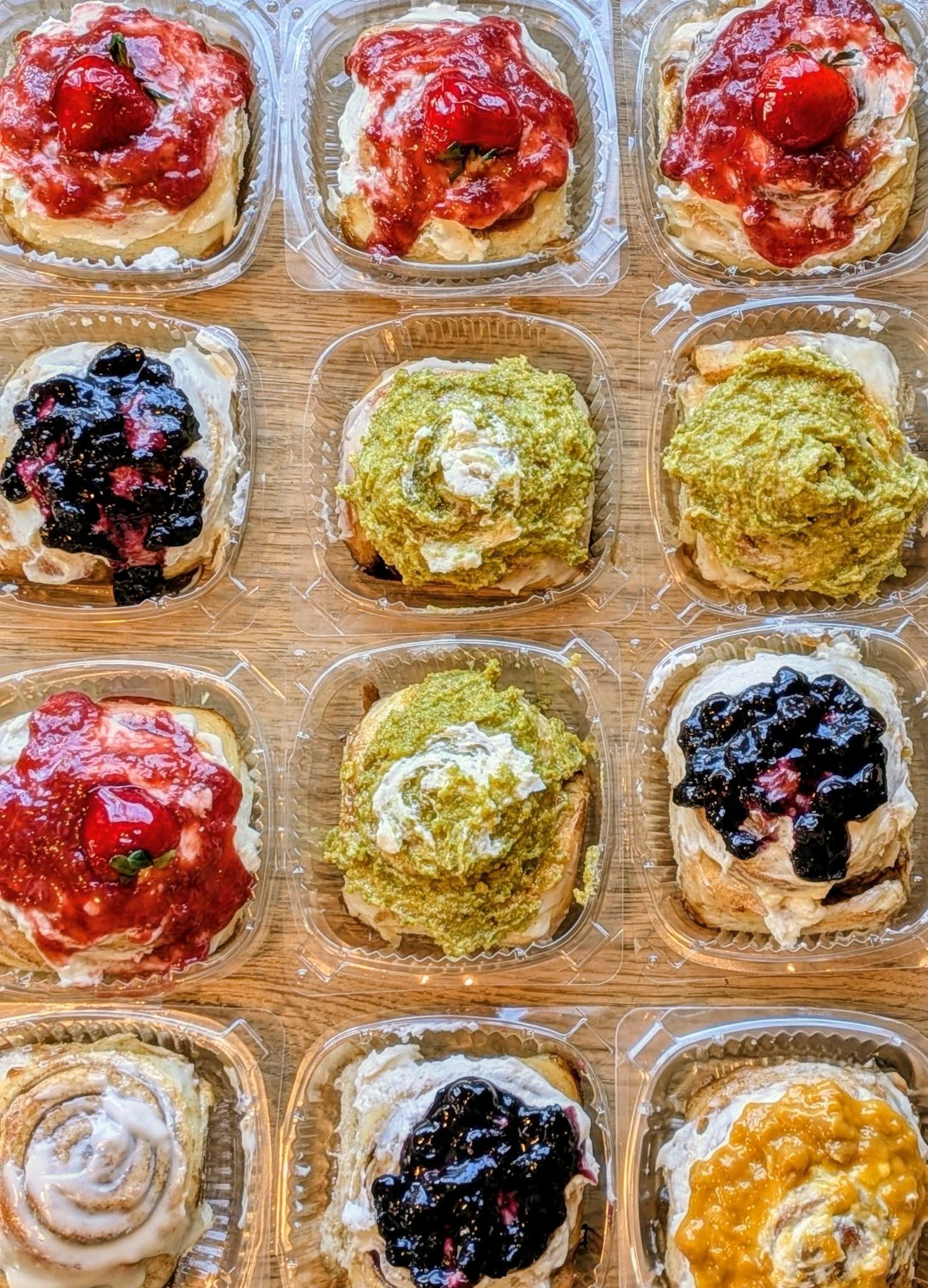 Overhead view of a tray of colorful pastries with various toppings like berries and pistachio.
