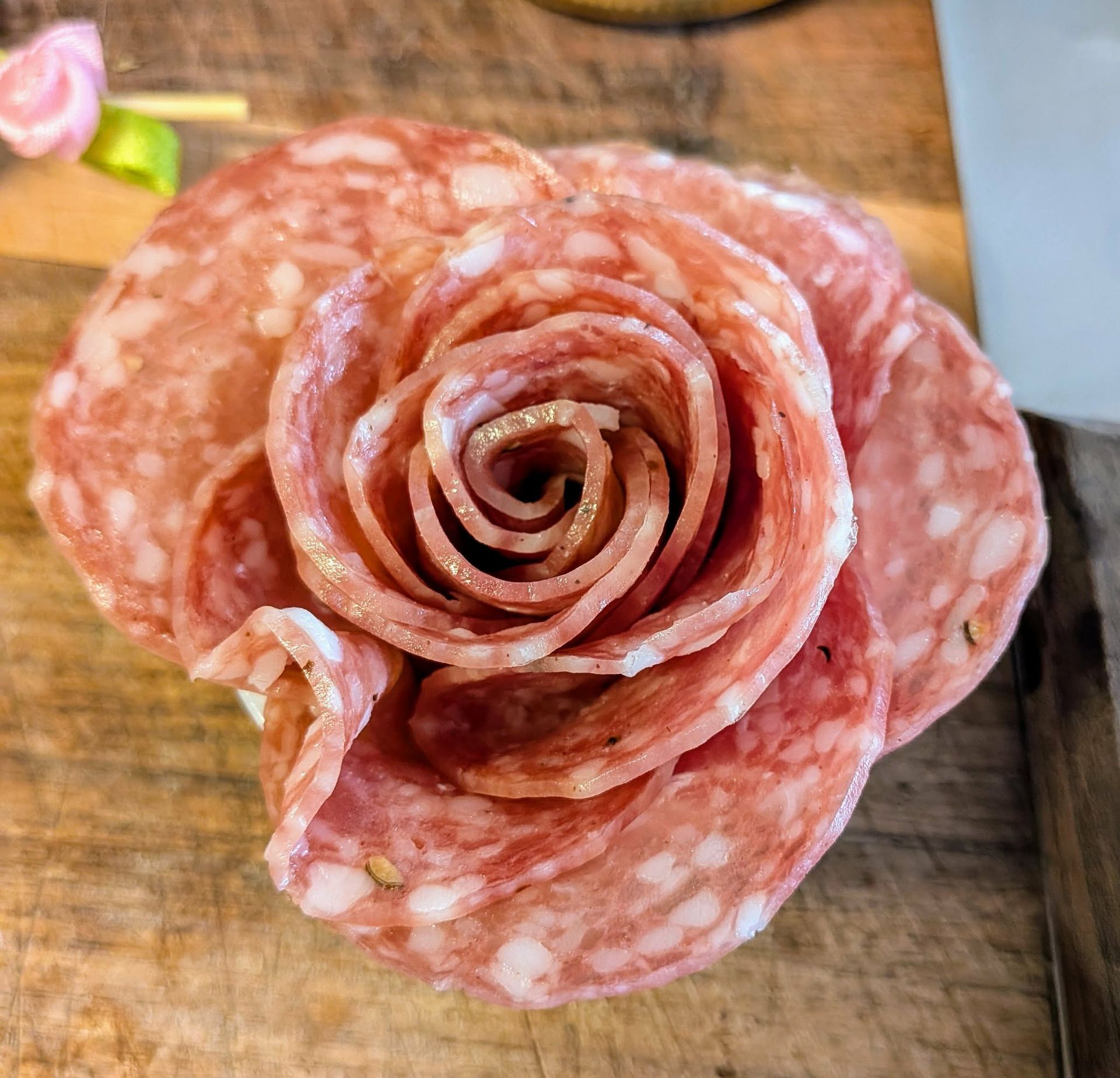 Salami slices arranged in a rose shape on a wooden board.