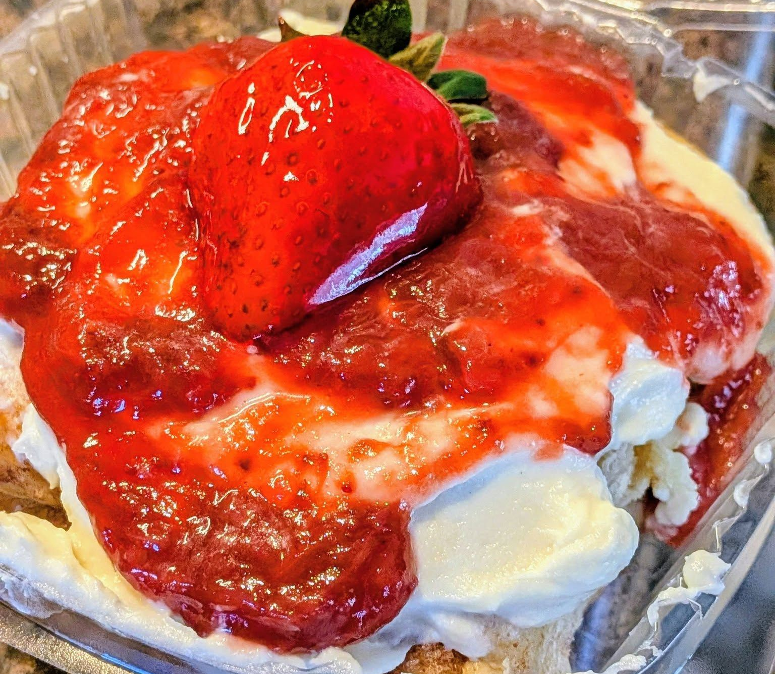Strawberry shortcake, featuring whipped cream, crushed strawberries, and a whole strawberry.
