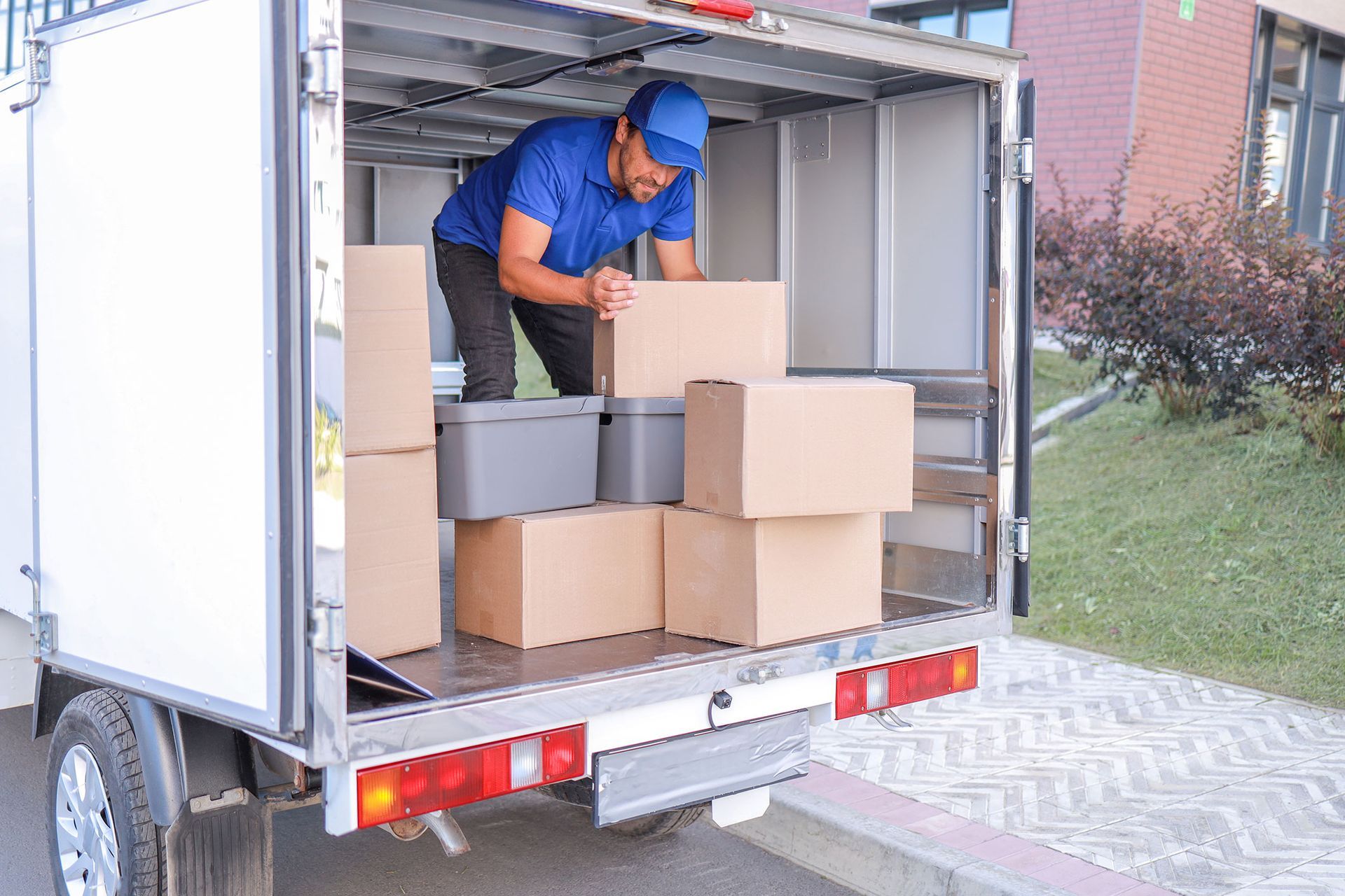 Delivery person loading cardboard boxes into a cargo truck.