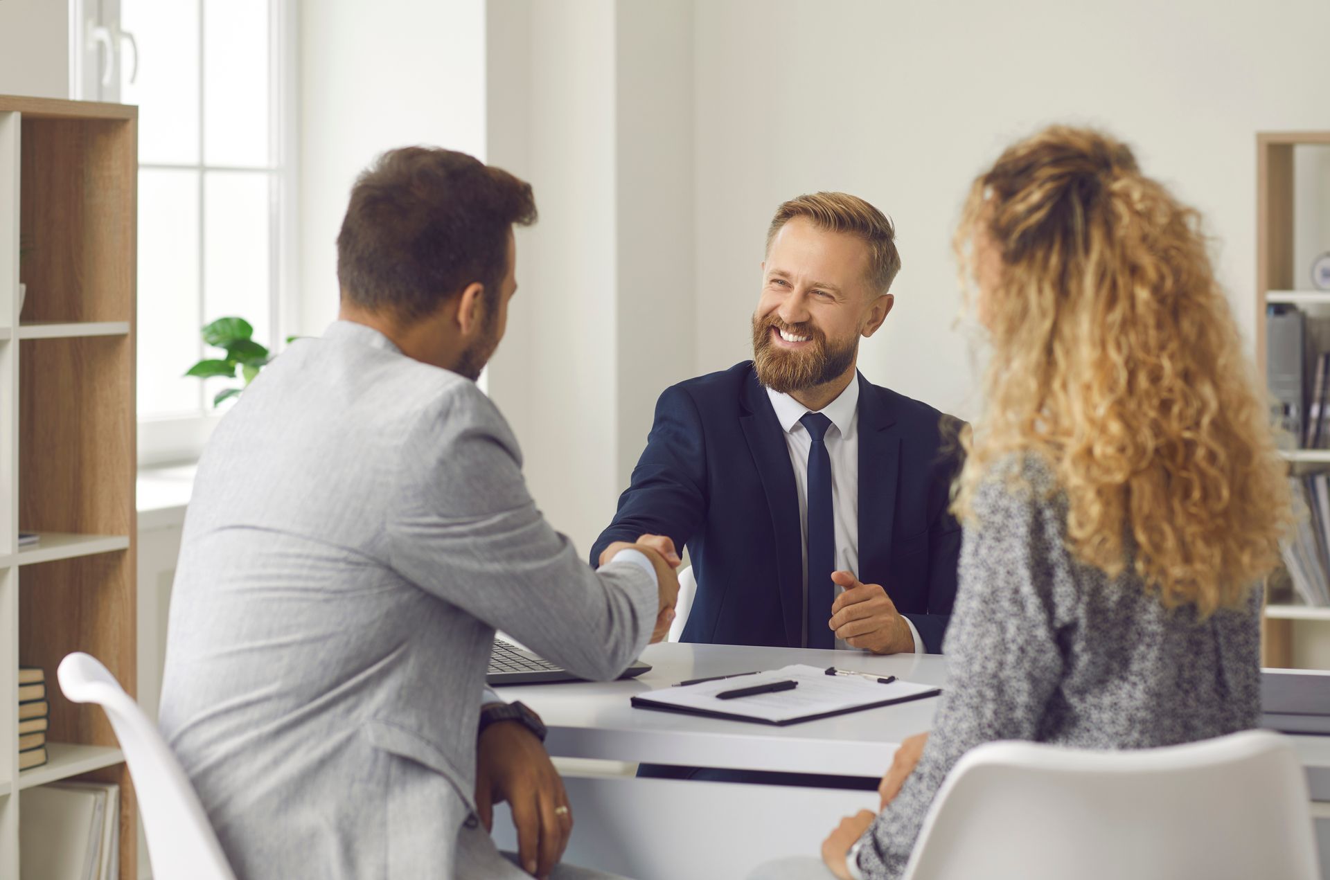 An agent shakes hands with clients during insurance consultations.