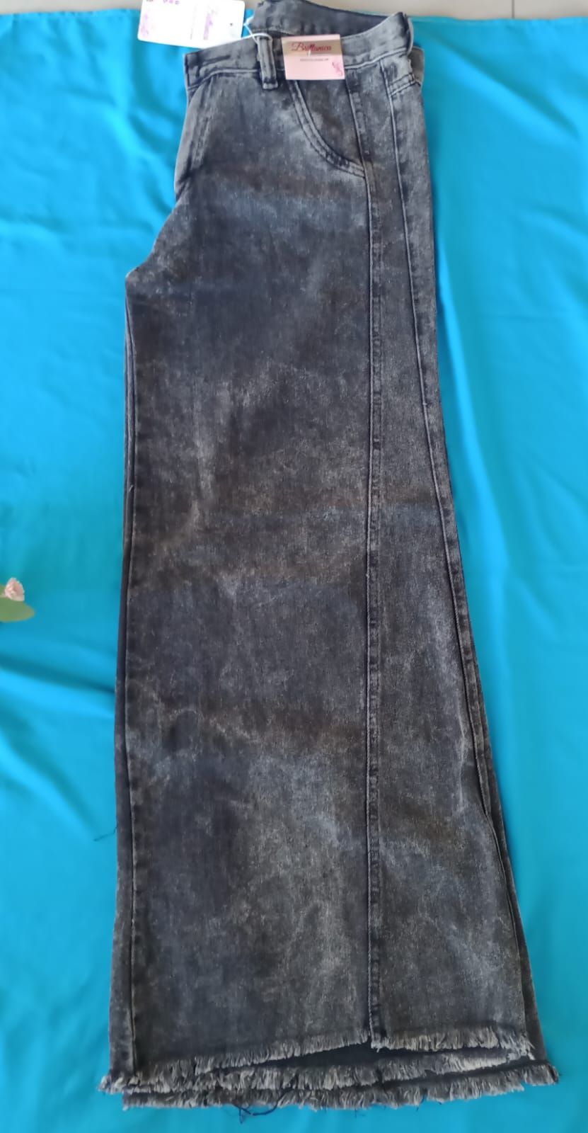 Un par de pantalones vaqueros de mezclilla color carbón con efecto desteñido, pernera acampanada.
