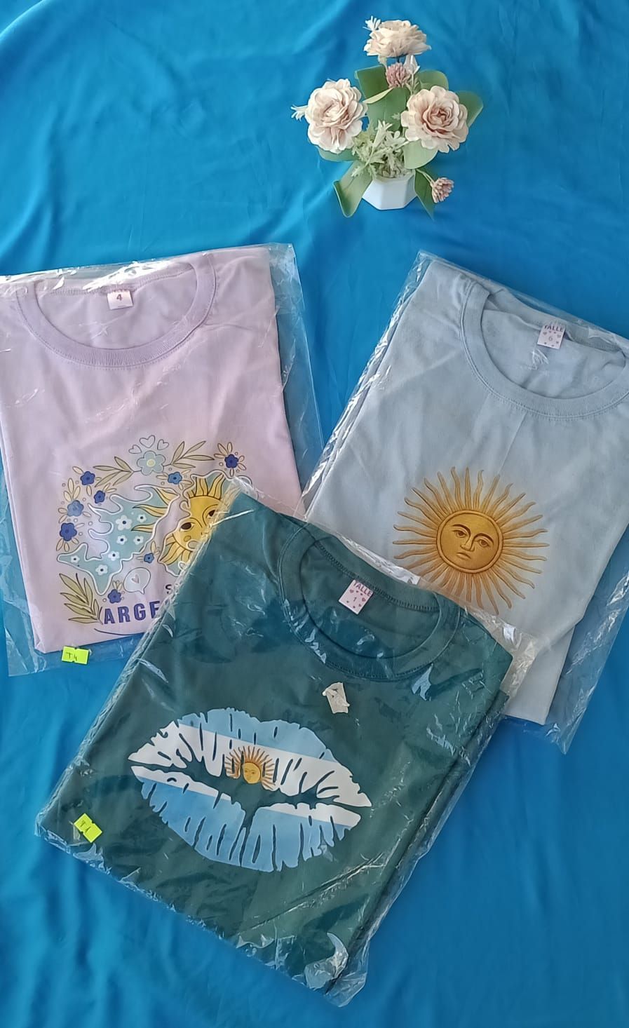 Una camiseta rosa claro con el dibujo de una empanada que lleva una bufanda argentina y sostiene un mate.