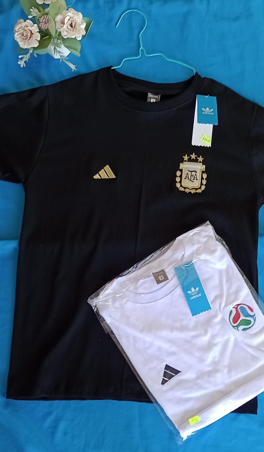 Una camiseta negra de manga corta con el logotipo dorado de Adidas y el escudo de la selección.