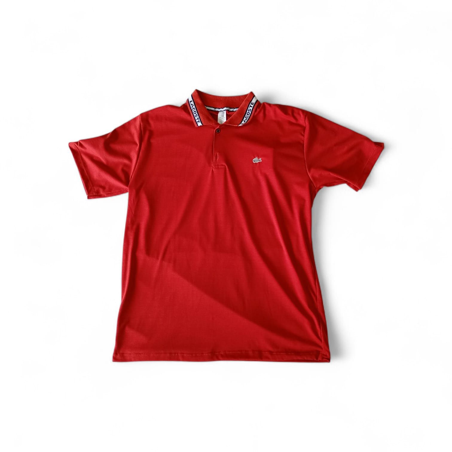 Una camisa polo roja brillante de manga corta con cuello estampado en blanco y negro, sobre un fondo blanco liso.