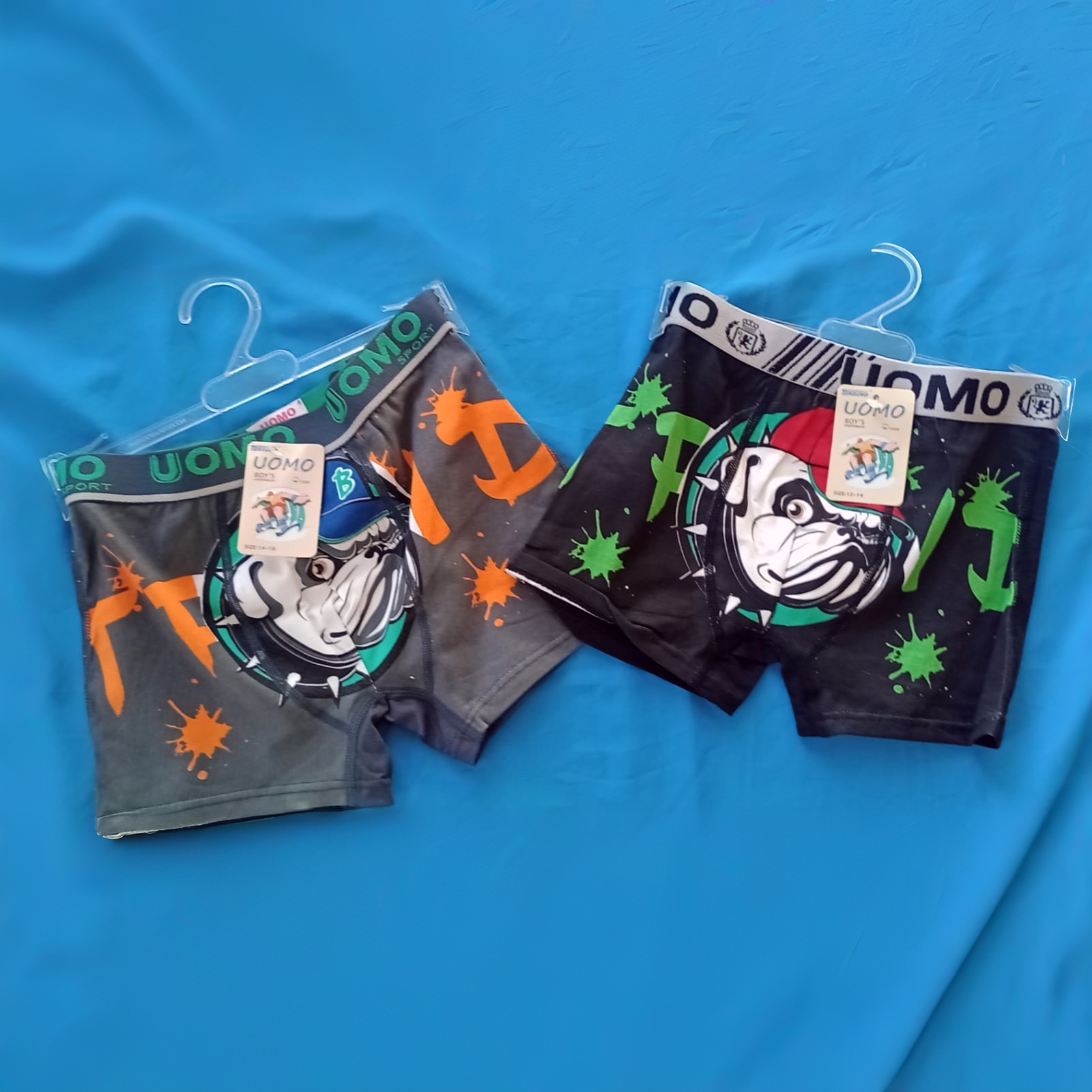 Dos pares de calzoncillos bóxer negros y grises colgados en perchas con dibujos de bulldogs.