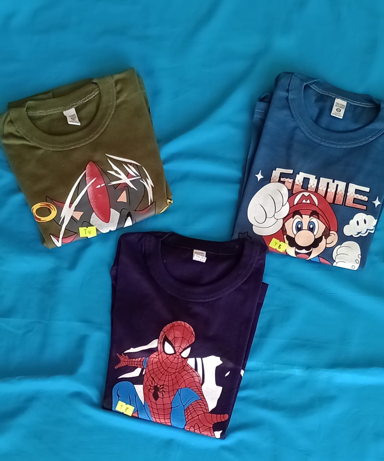 Una camisa azul oscuro de manga larga con un gráfico de Amazing Spider-Man sobre un fondo de tela turquesa.