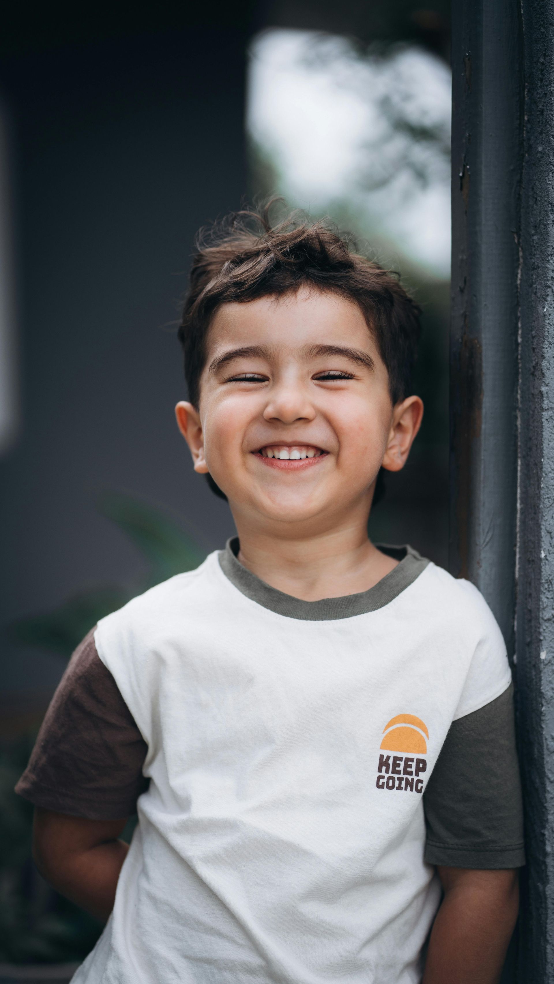 Un niño con el pelo revuelto, vestido con una camisa blanca y marrón.