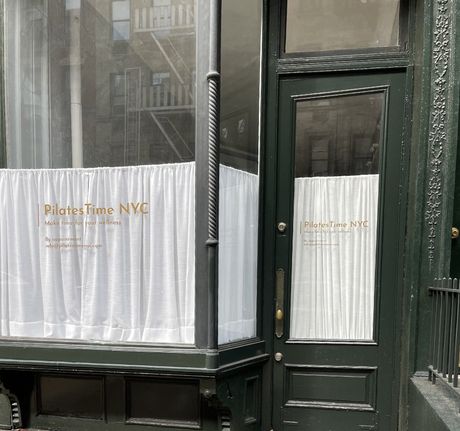 A store front with a sign that says pilates time nyc