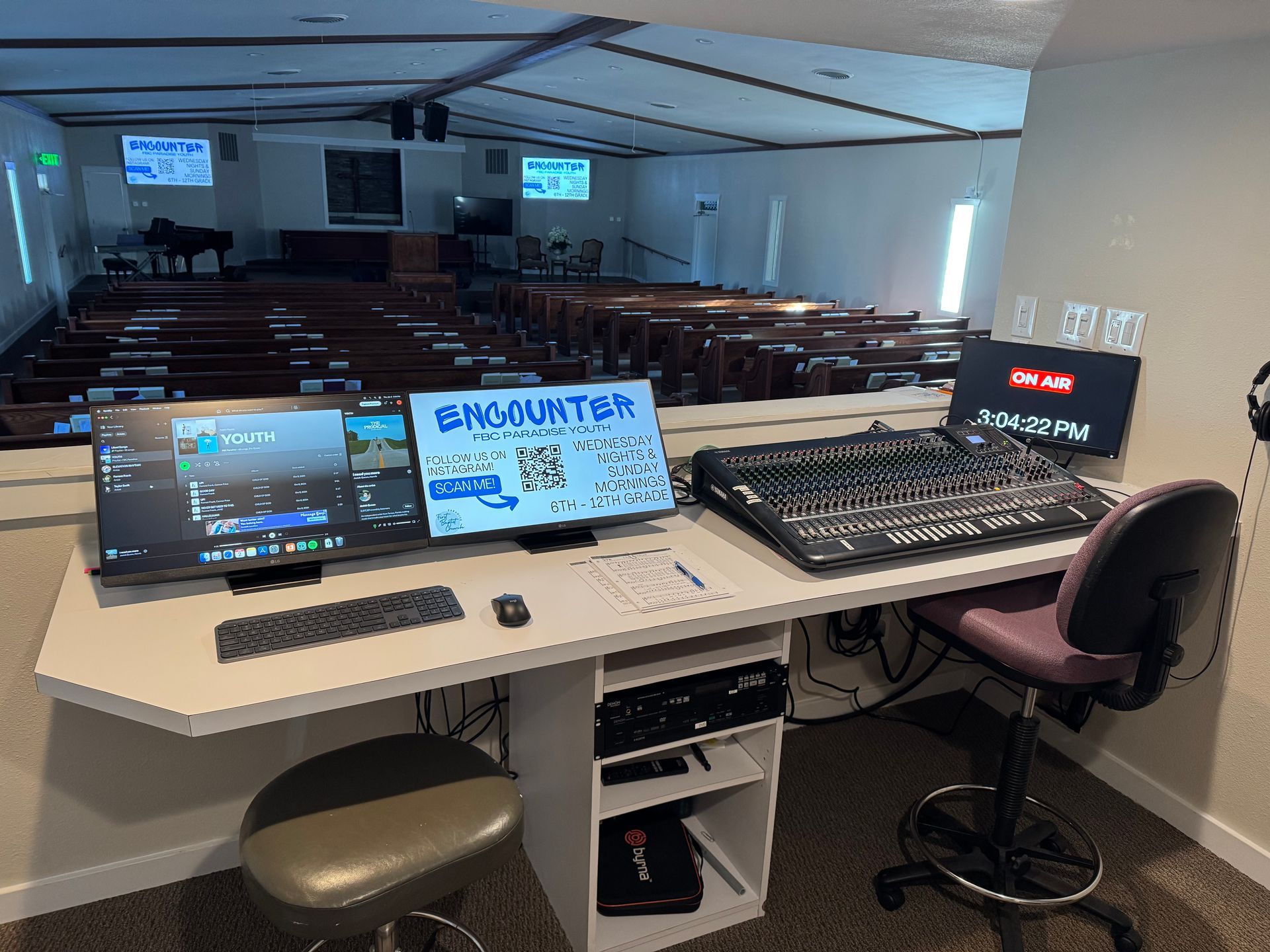 A recording studio in a church with two monitors and a mixer.