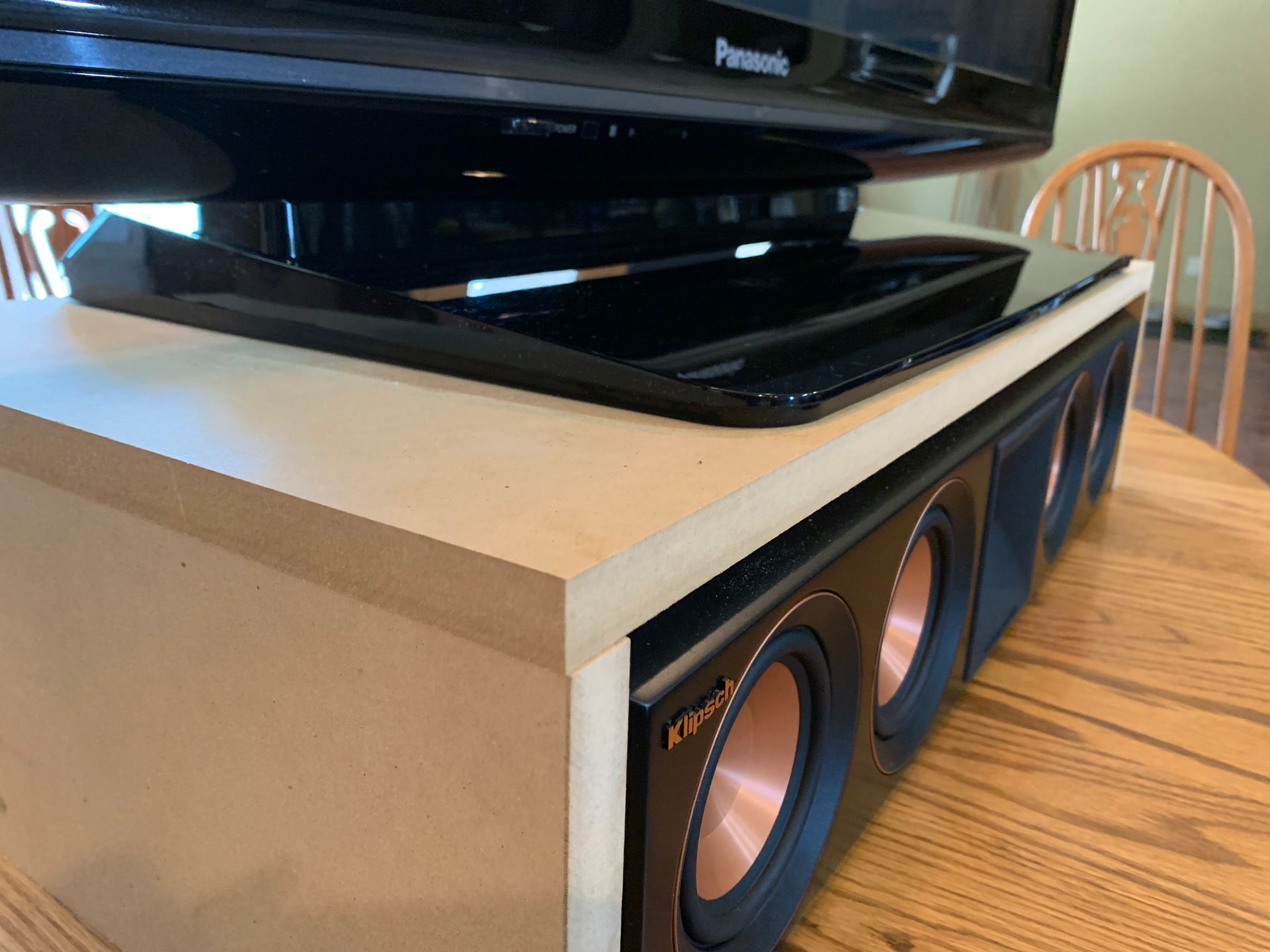 A tv is sitting on top of a wooden table next to a speaker.