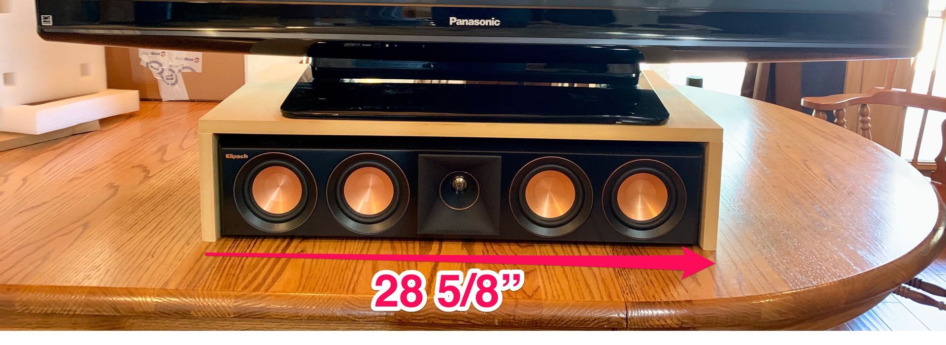 A tv is sitting on a wooden table next to a speaker box.