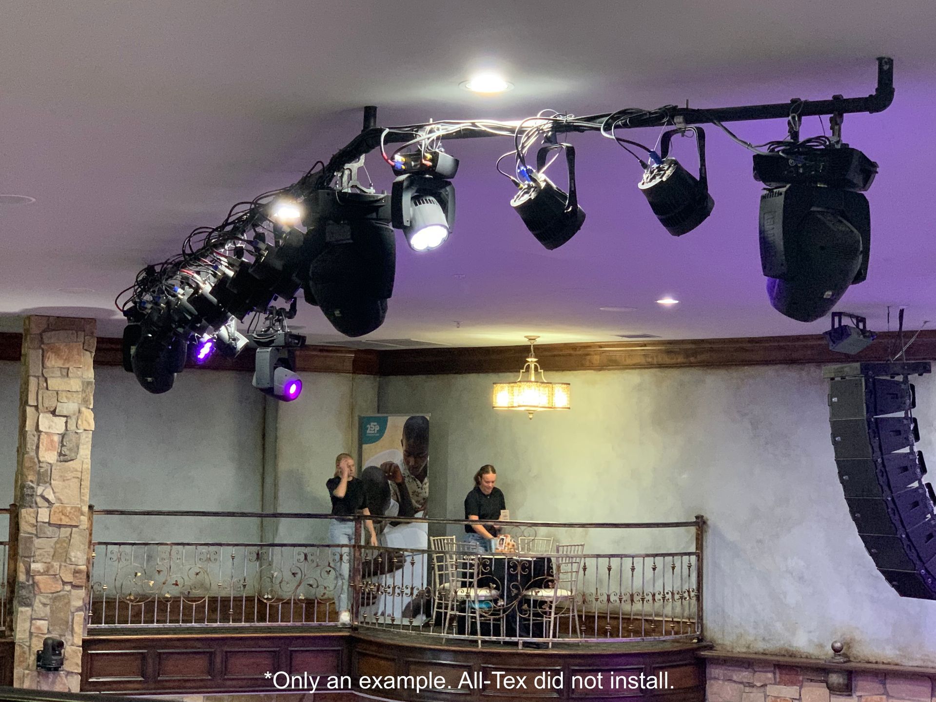 A man is sitting at a table in a room with a lot of lights hanging from the ceiling.
