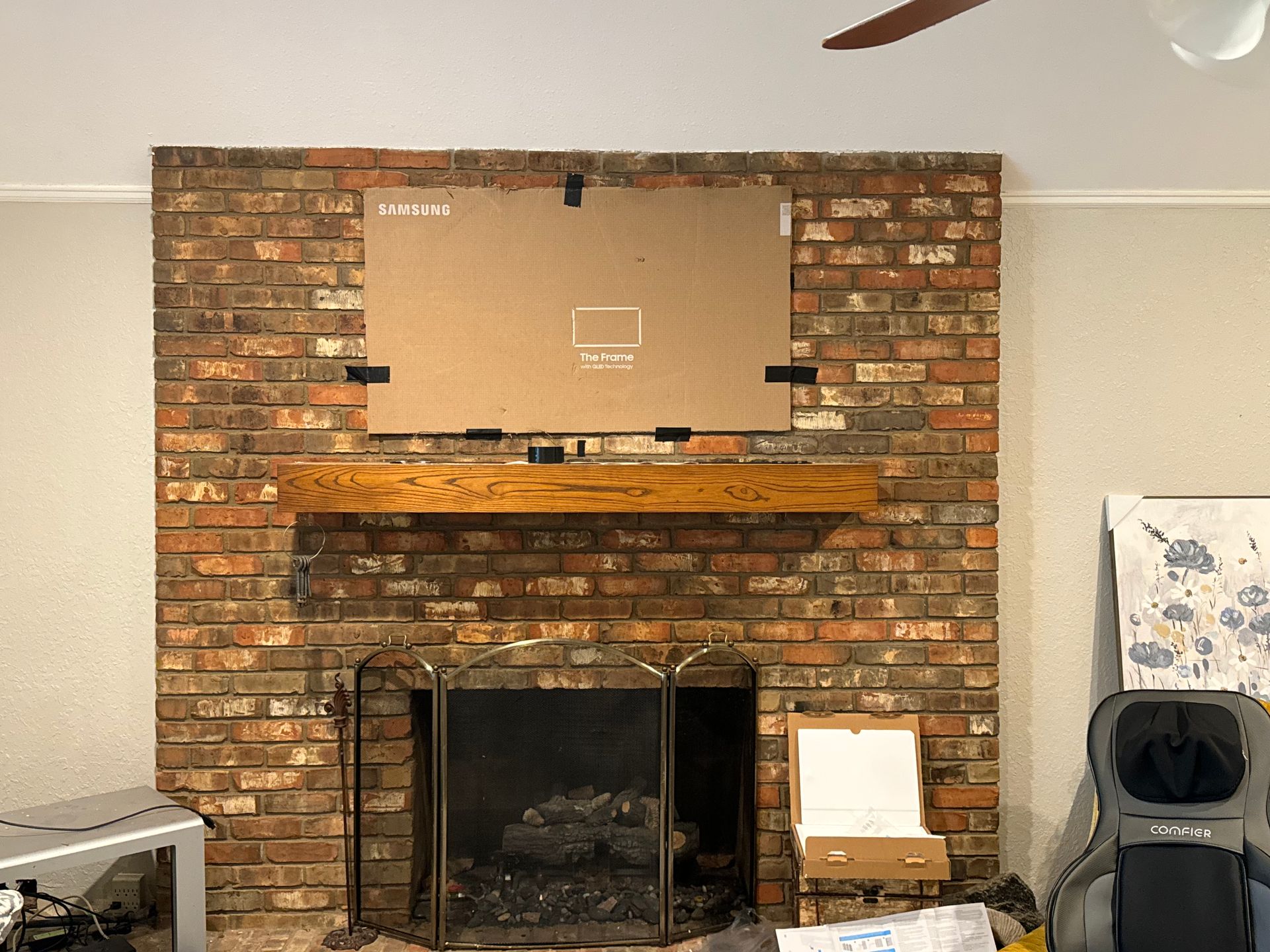 A living room with a brick fireplace and a ceiling fan