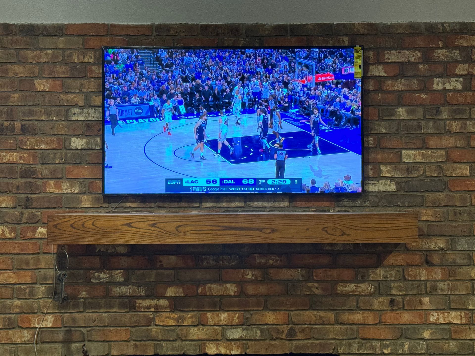 A flat screen tv is hanging on a brick wall above a fireplace.