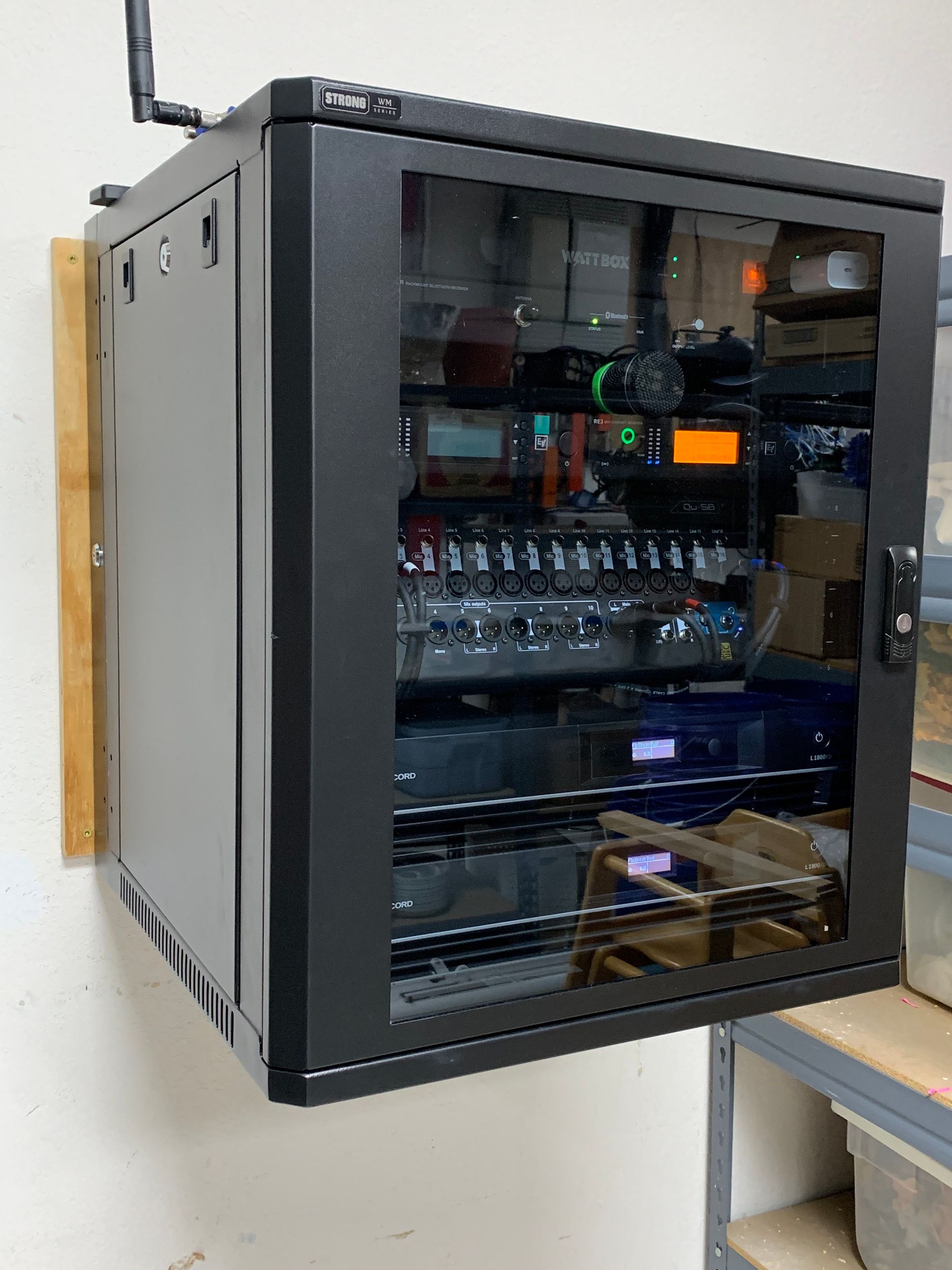 A black cabinet with a glass door is hanging on a wall.