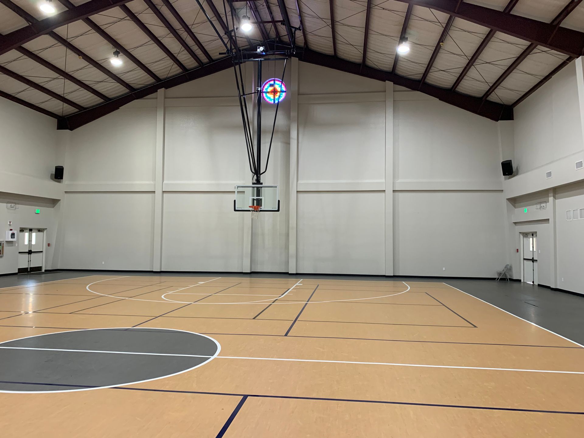 A large indoor basketball court with a stained glass window in the background.