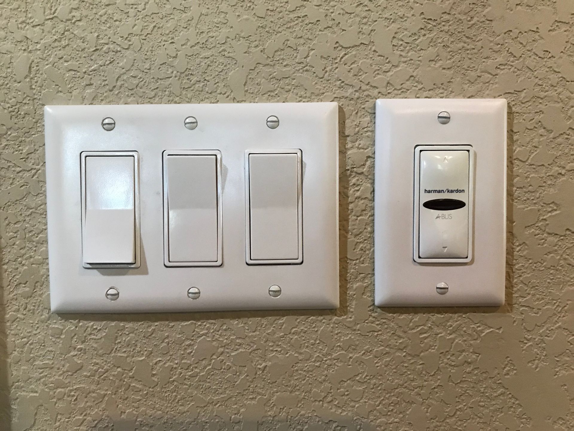 Two white light switches are on a wall next to each other.