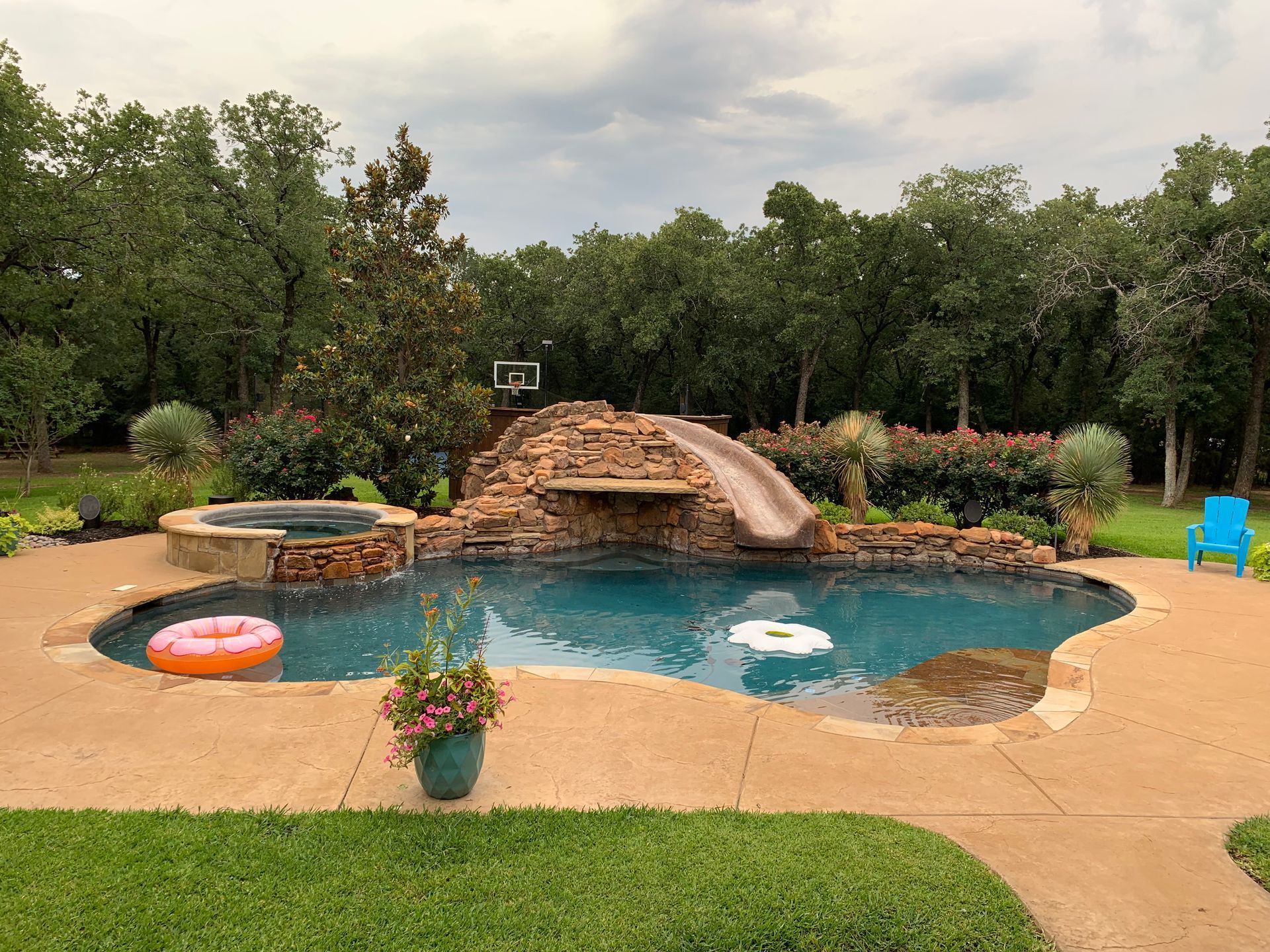 A large swimming pool with a slide and a waterfall in the backyard.