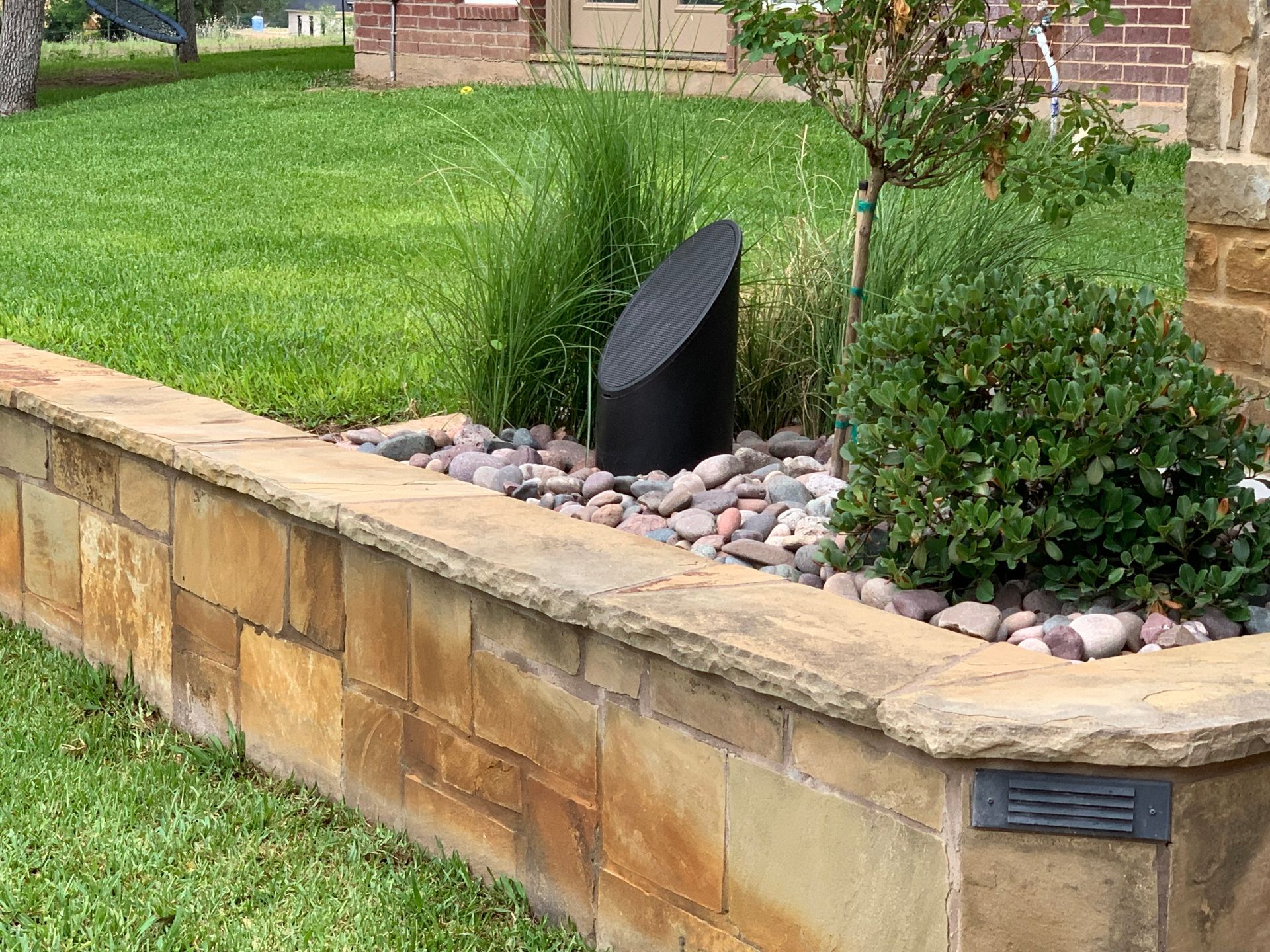 A stone wall with a speaker in the middle of it.