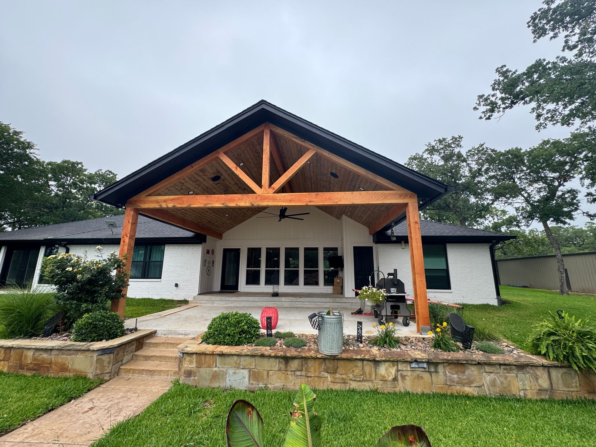 A white house with a wooden porch and a black roof.